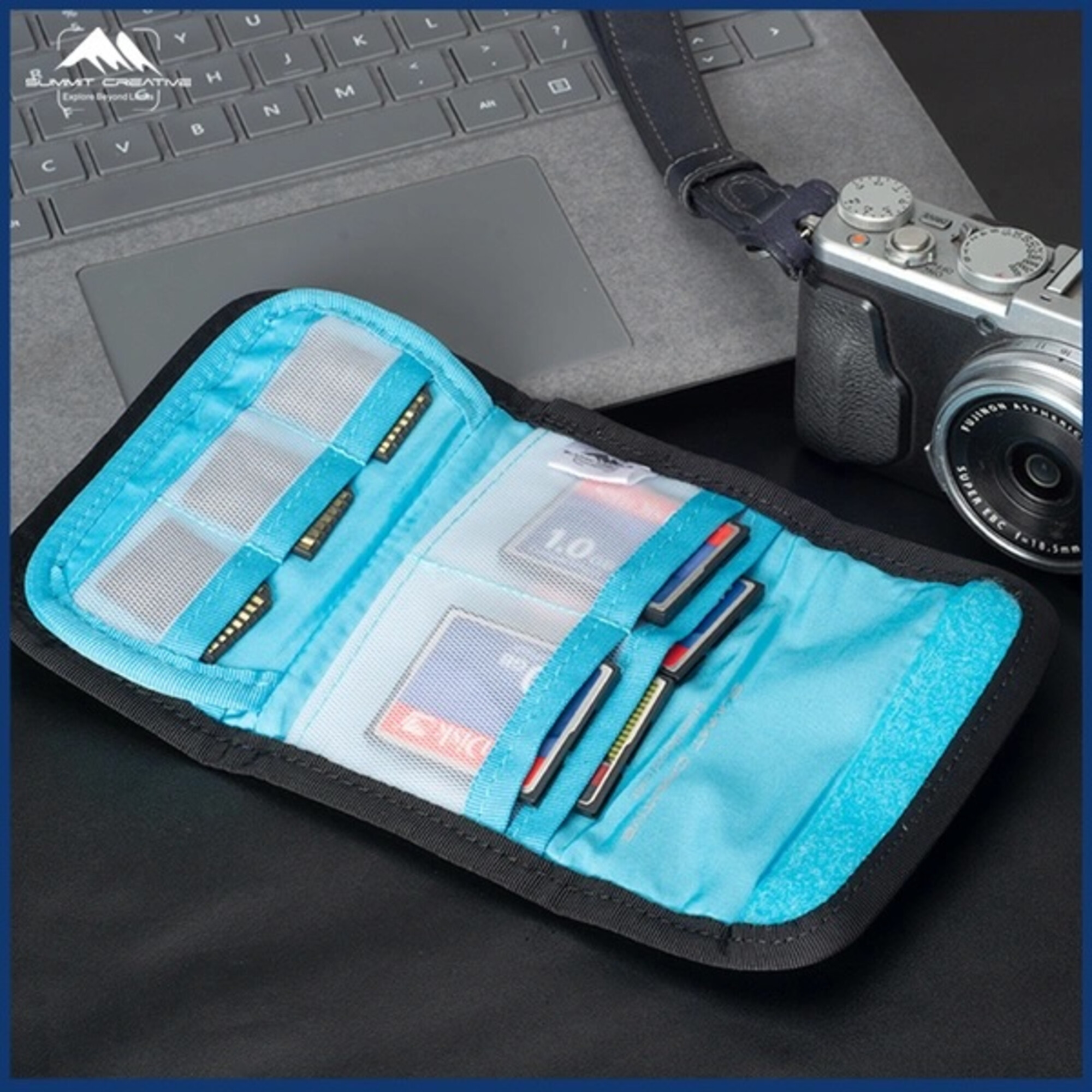 Eine blaue Speicherkartenhülle mit SD- und CF-Karten liegt neben einer Kamera und einem Laptop.