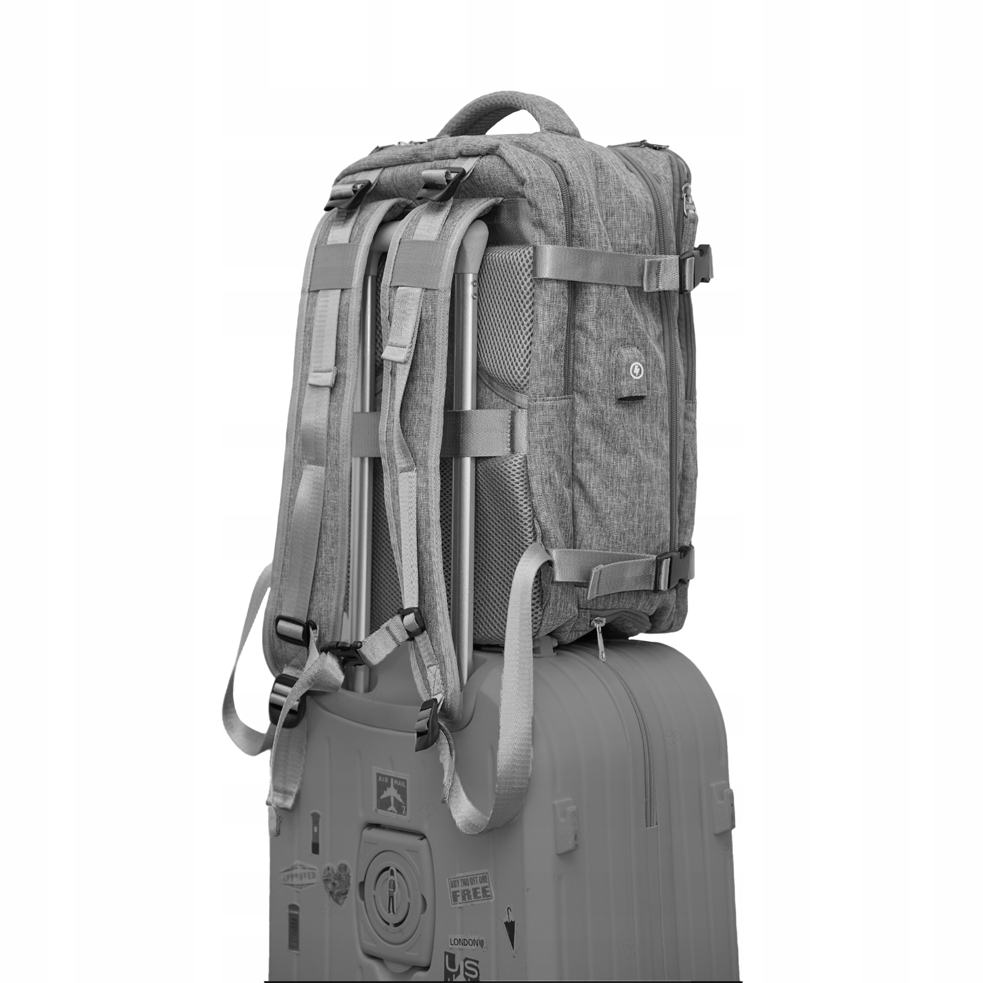 Szary plecak na szarej walizce ze srebrnym uchwytem.