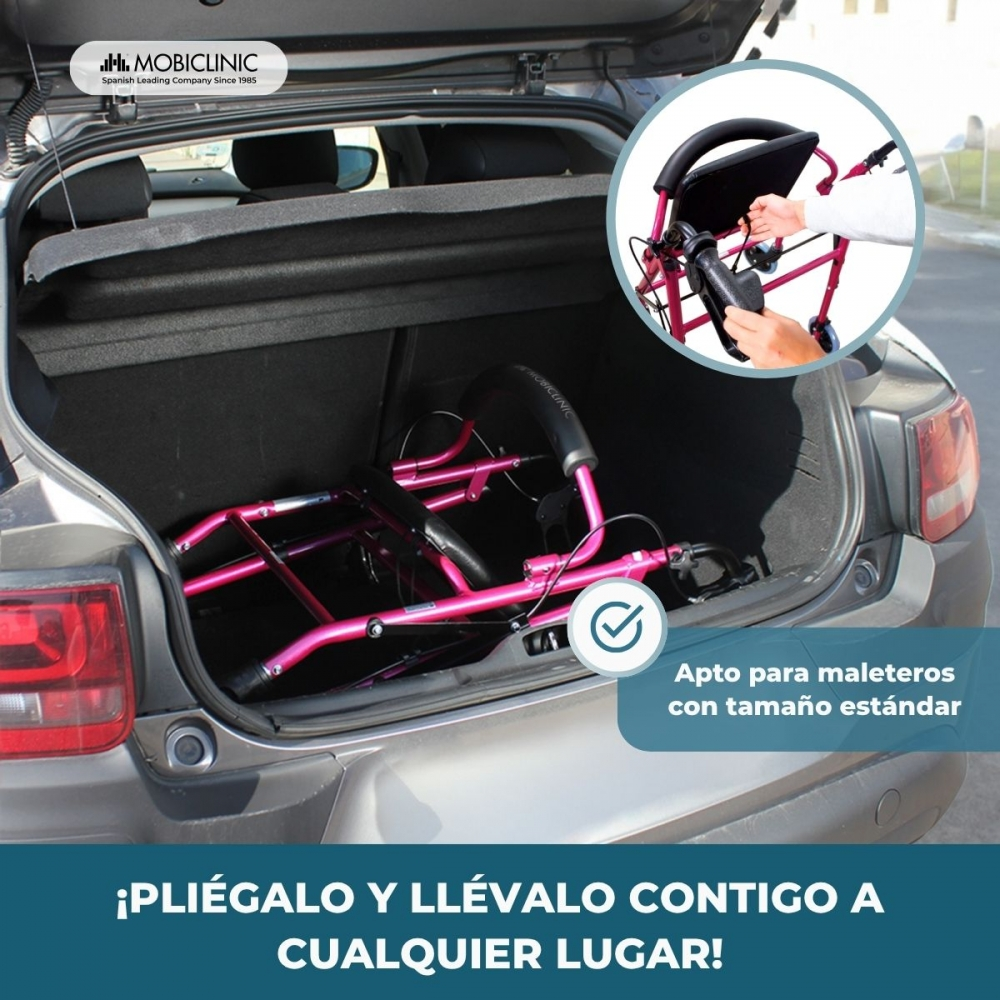 Un andador rosa plegado en el maletero de un coche. Cabe en maleteros estándar.
