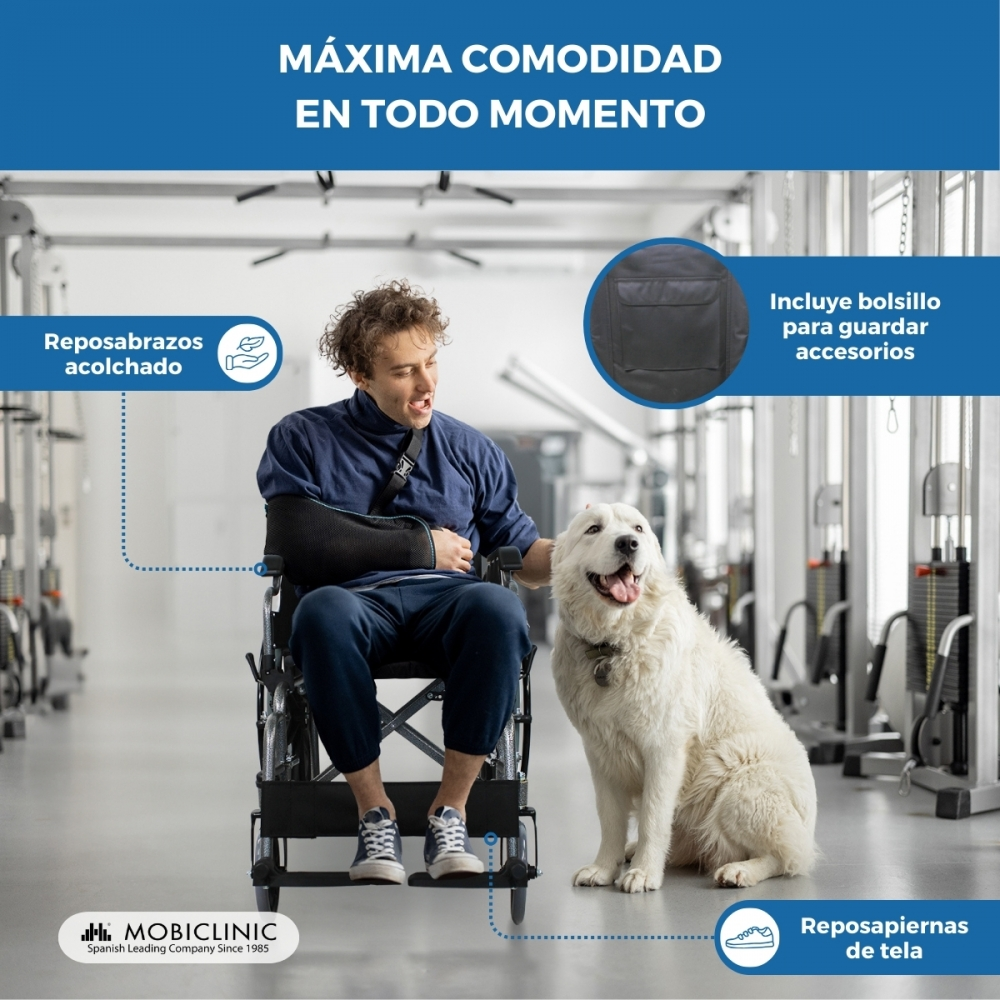 Hombre en silla de ruedas con cabestrillo y perro en gimnasio. Reposabrazos acolchados.