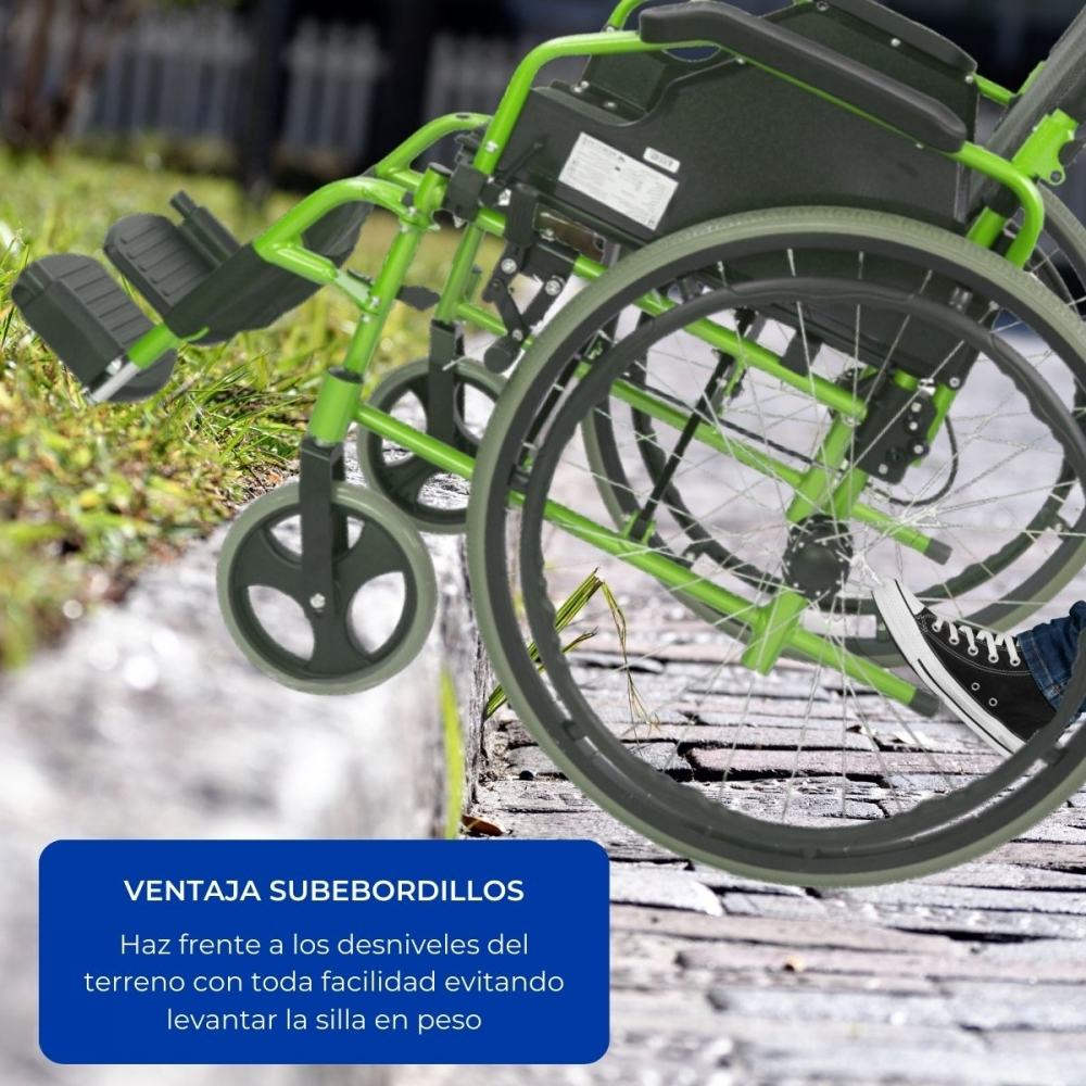 Una silla de ruedas verde con ruedas grandes está sobre un camino pavimentado junto a césped.