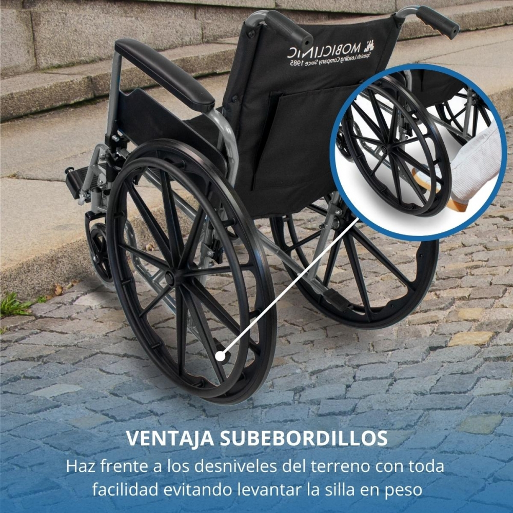 Una silla de ruedas negra descansa en un camino de piedras. Un detalle muestra una rueda.
