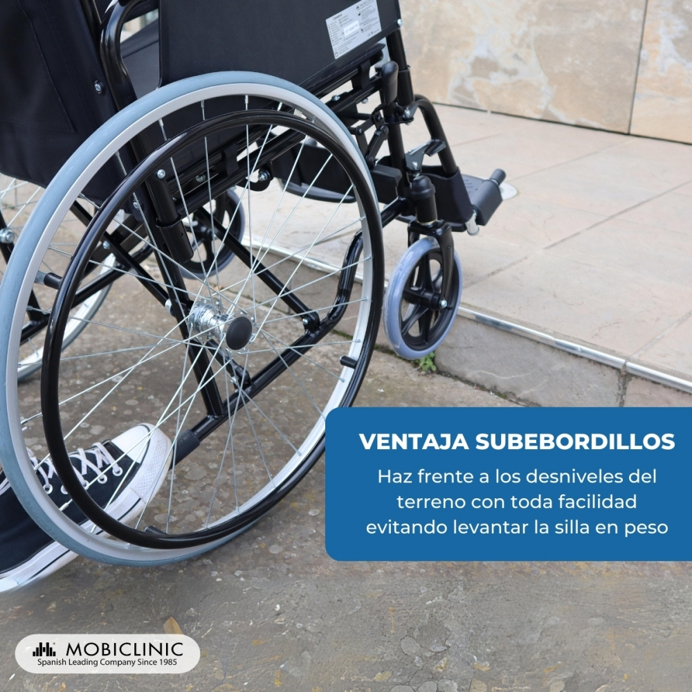Un sillón de ruedas con ruedas de radios grandes y una rueda delantera pequeña, subiendo un bordillo.