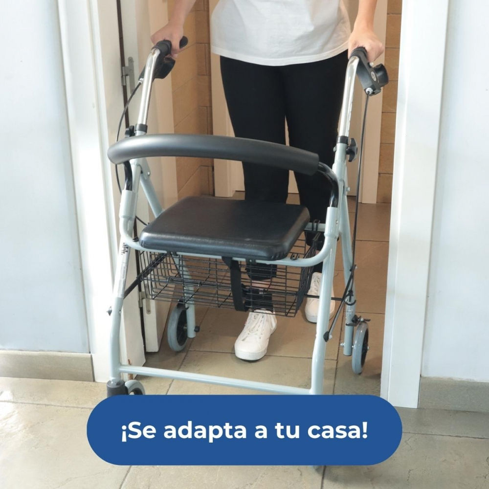 Una persona detrás de un andador con asiento y cesta. Está en un pasillo.