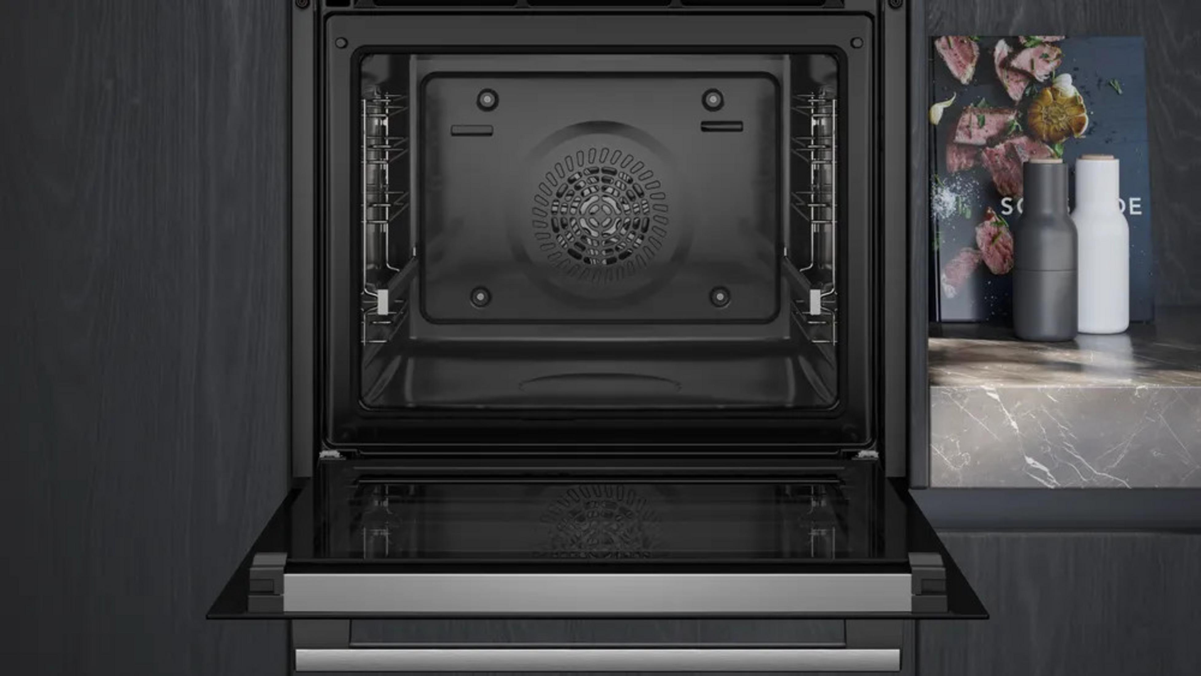 Un forno moderno con la porta aperta, nero dentro e fuori.