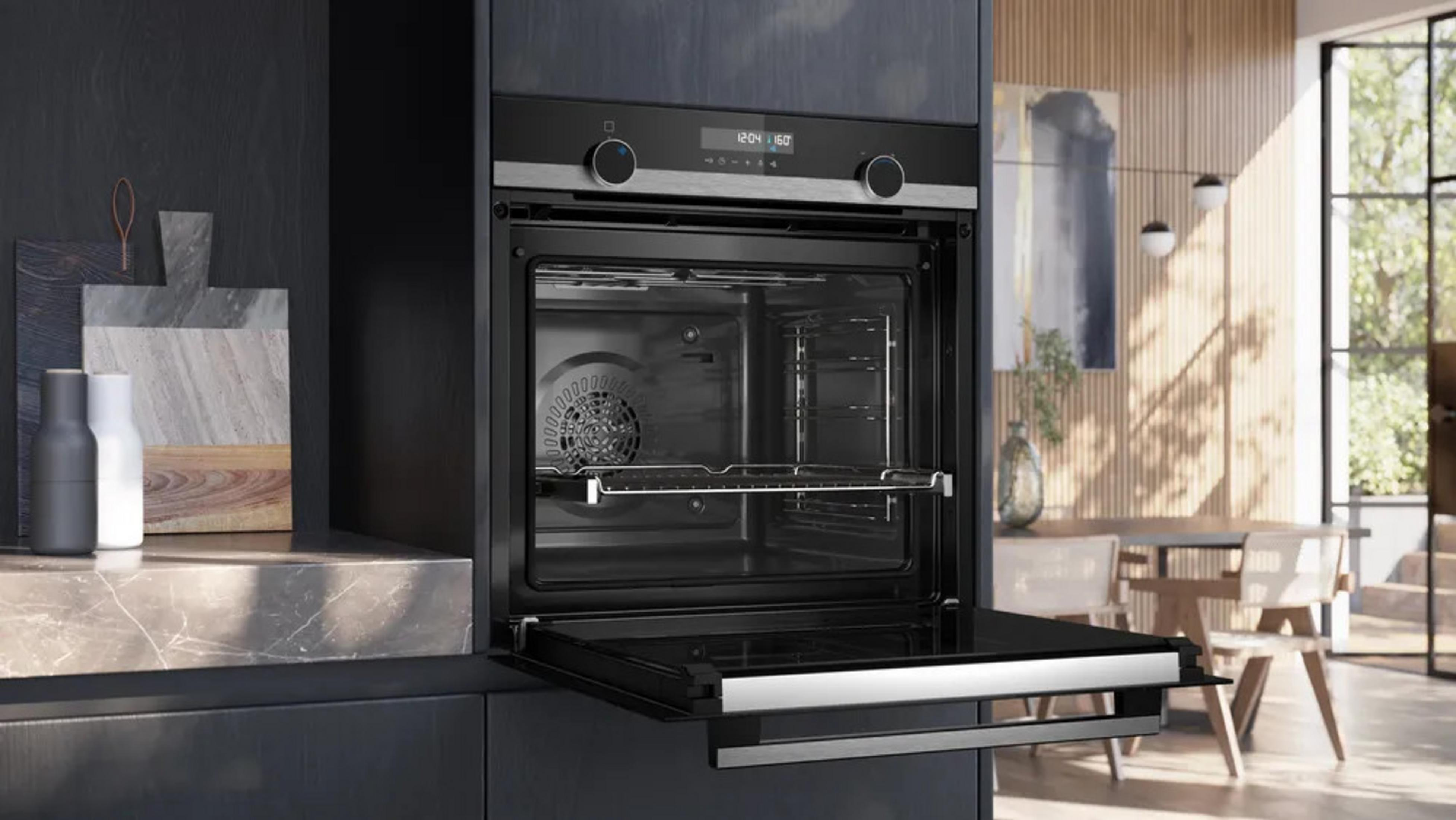 Un forno da incasso moderno con la porta aperta, accanto a utensili da cucina.