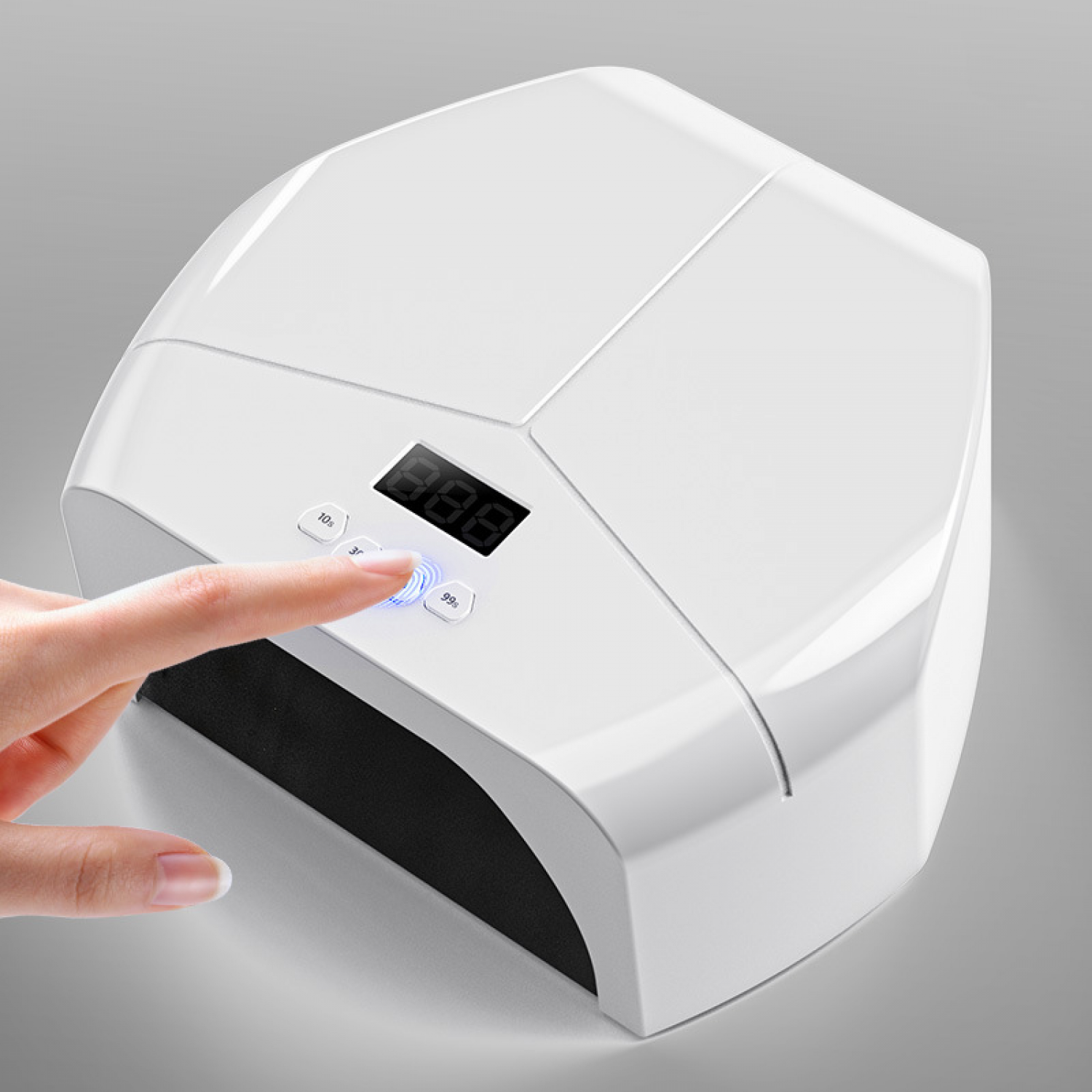 Eine Hand drückt auf den Knopf einer weißen UV-Nagellampe mit Digitalanzeige.