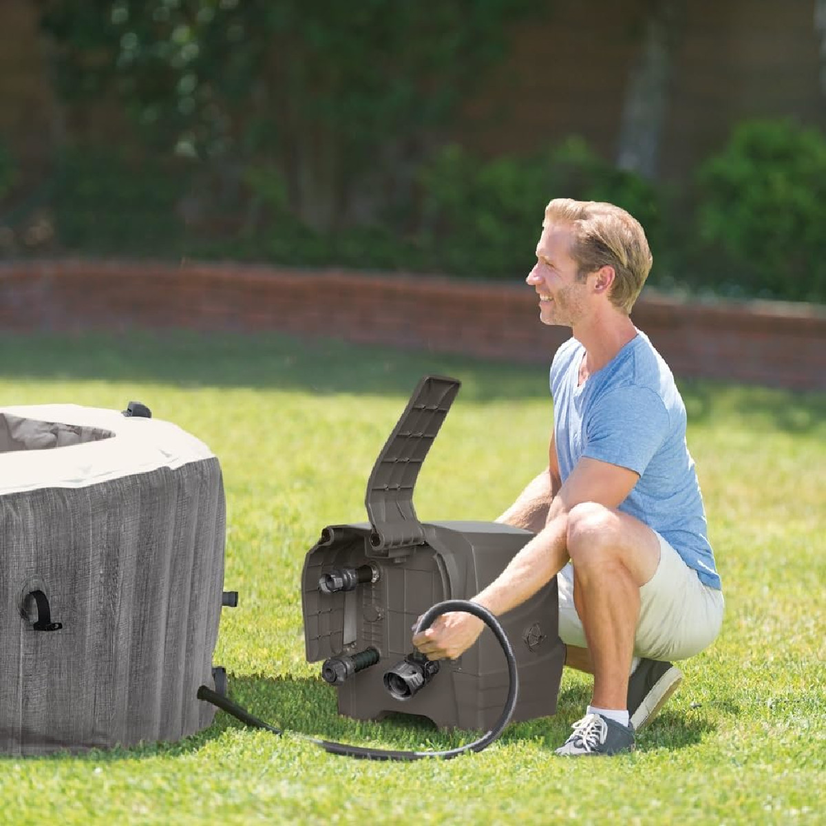 Mann repariert aufblasbaren Whirlpool mit Pumpe und Schlauch im Garten.
