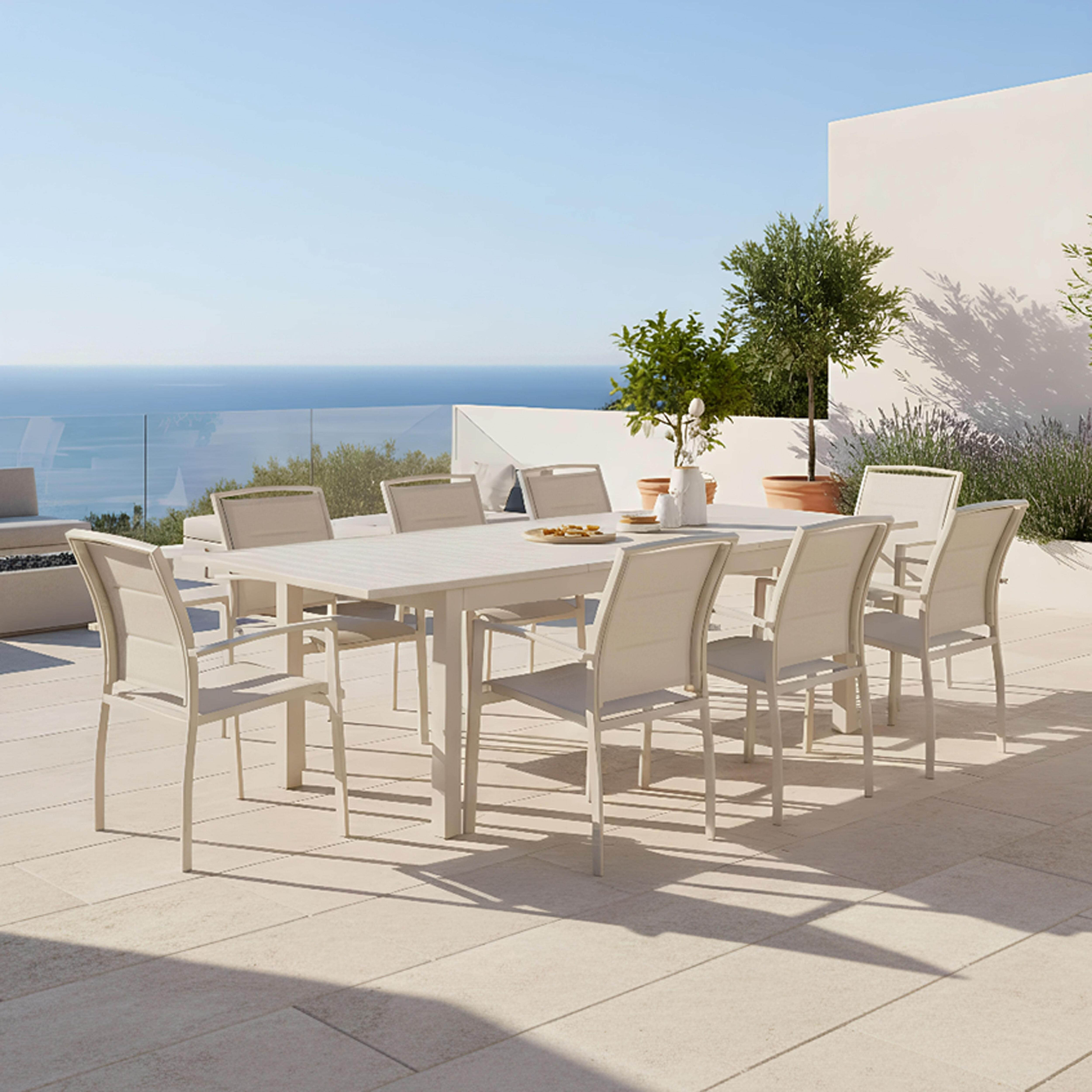 Weiße Gartenmöbel mit Tisch und Stühlen auf einer Terrasse mit Meerblick.