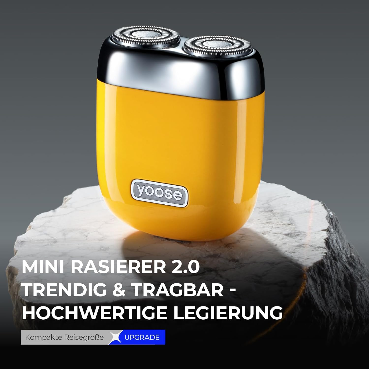 Ein gelber Mini-Rasierer mit silbernem Oberteil auf einem Stein.