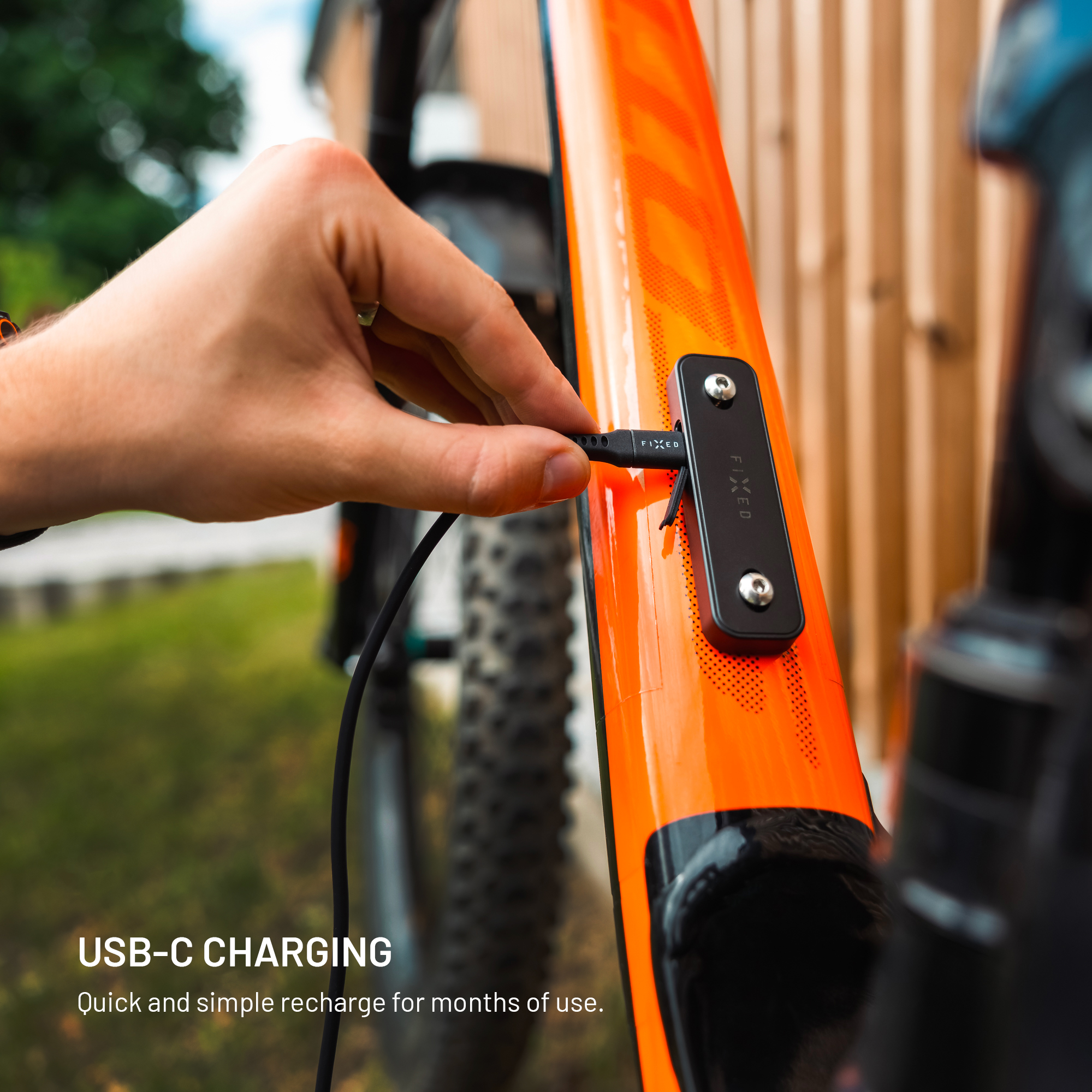 Ein Mann steckt ein USB-C-Kabel in ein orangefarbenes Fahrrad.