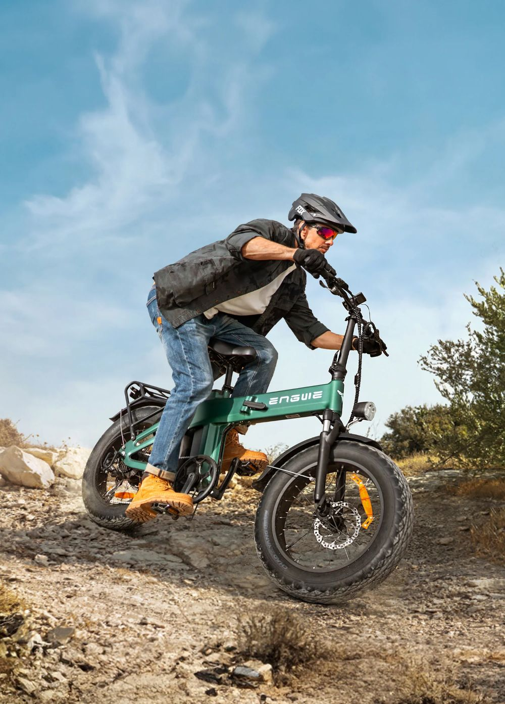 Un uomo guida una bicicletta elettrica verde su un sentiero sterrato roccioso.
