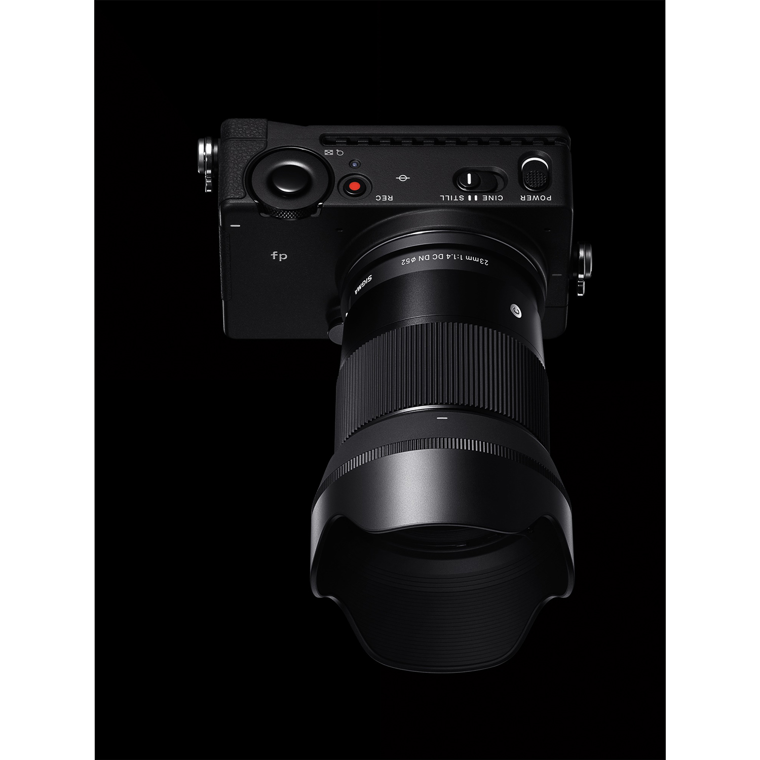 Una fotocamera Sigma fp nera con obiettivo da 23mm e paraluce, isolata su sfondo nero.