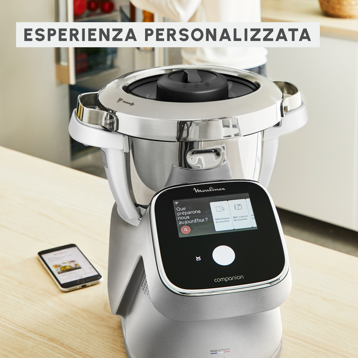 Un robot da cucina Moulinex con touchscreen e smartphone accanto su un tavolo di legno.