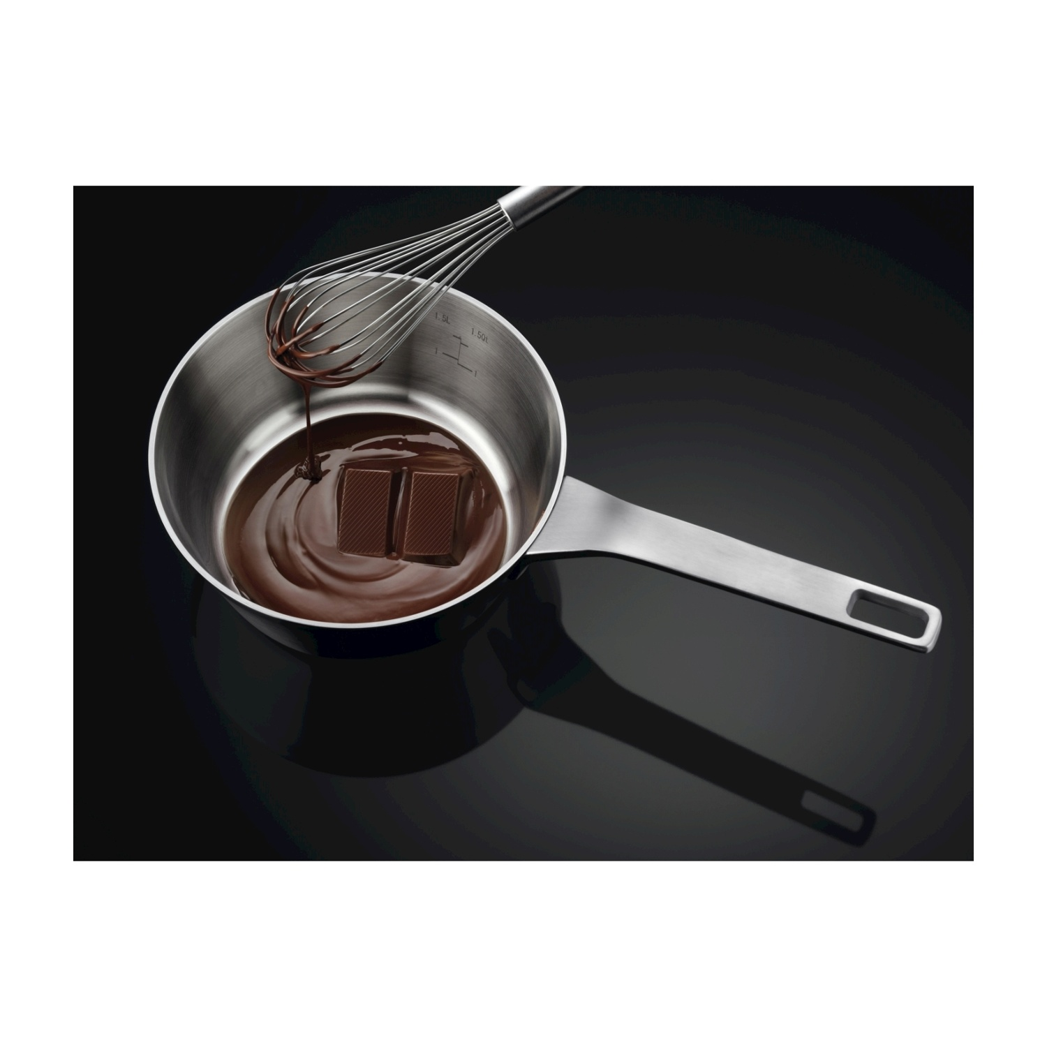 Pentola in acciaio inox con cioccolato fuso e frusta.