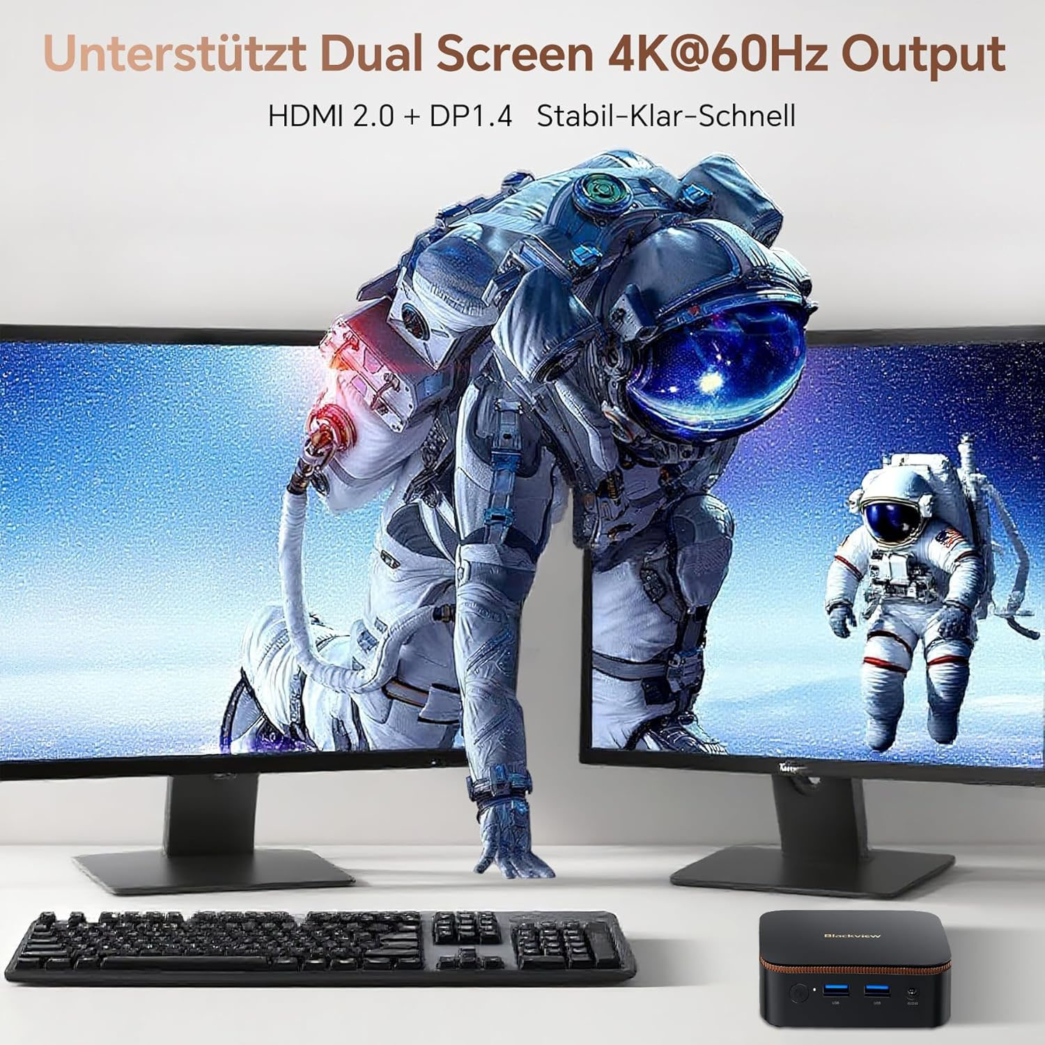 Zwei Monitore zeigen Astronauten. Ein Mini-PC und Tastatur sind davor.