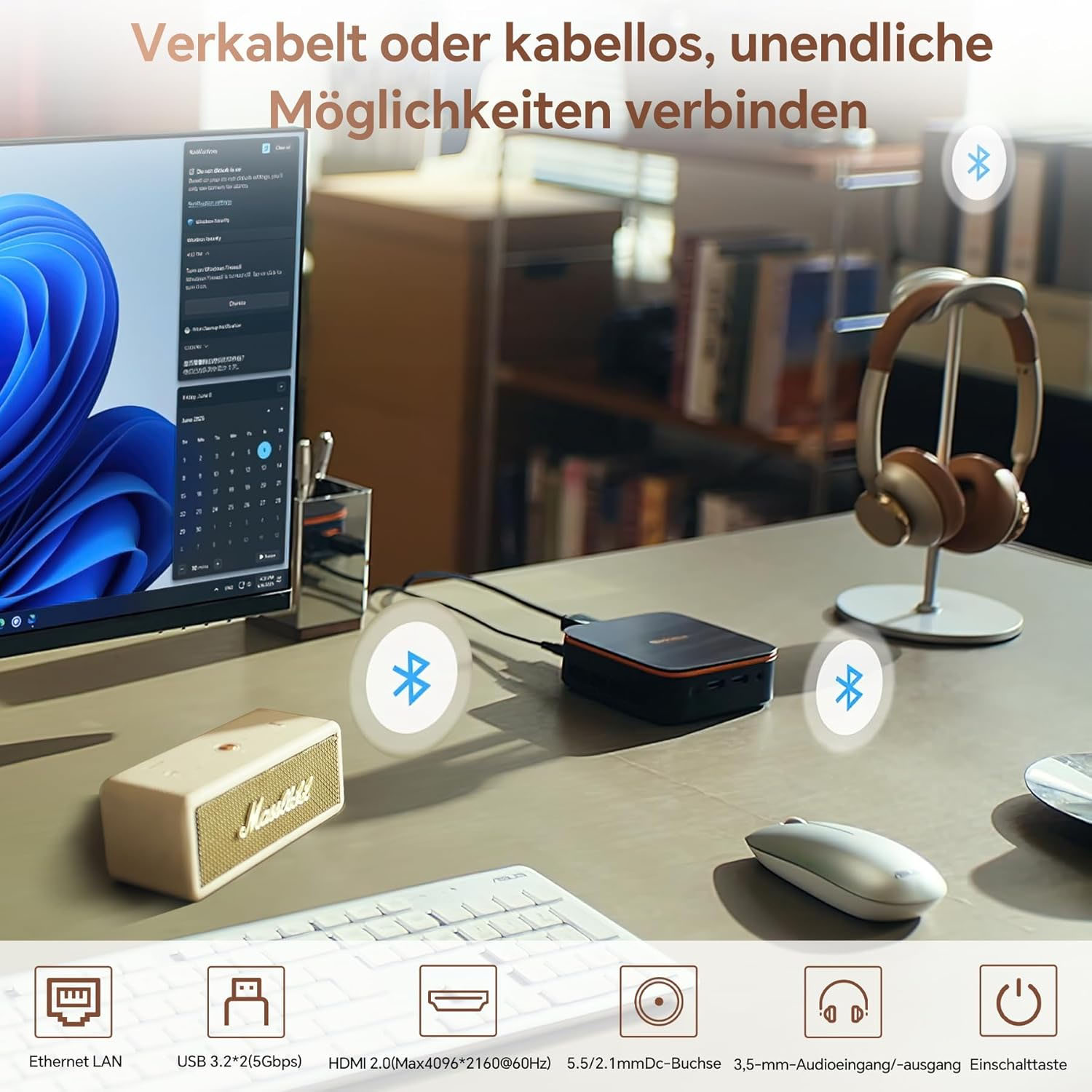 Ein Schreibtisch mit Computer, Kopfhörern, Maus, Tastatur und Lautsprecher.