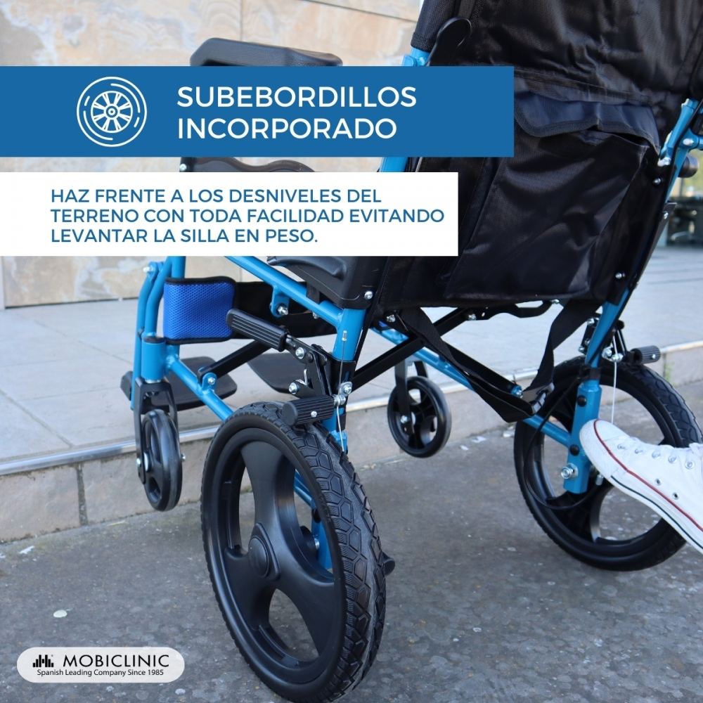 Una silla de ruedas azul con ruedas traseras grandes y delanteras pequeñas. Se ve un pie con zapatilla blanca.