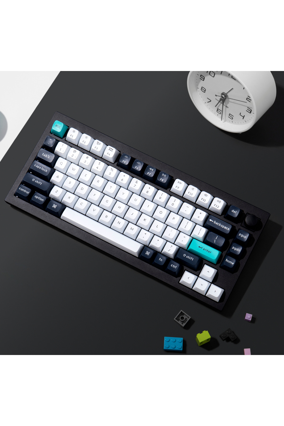 Un teclado negro con teclas blancas y turquesas descansa sobre una superficie oscura.