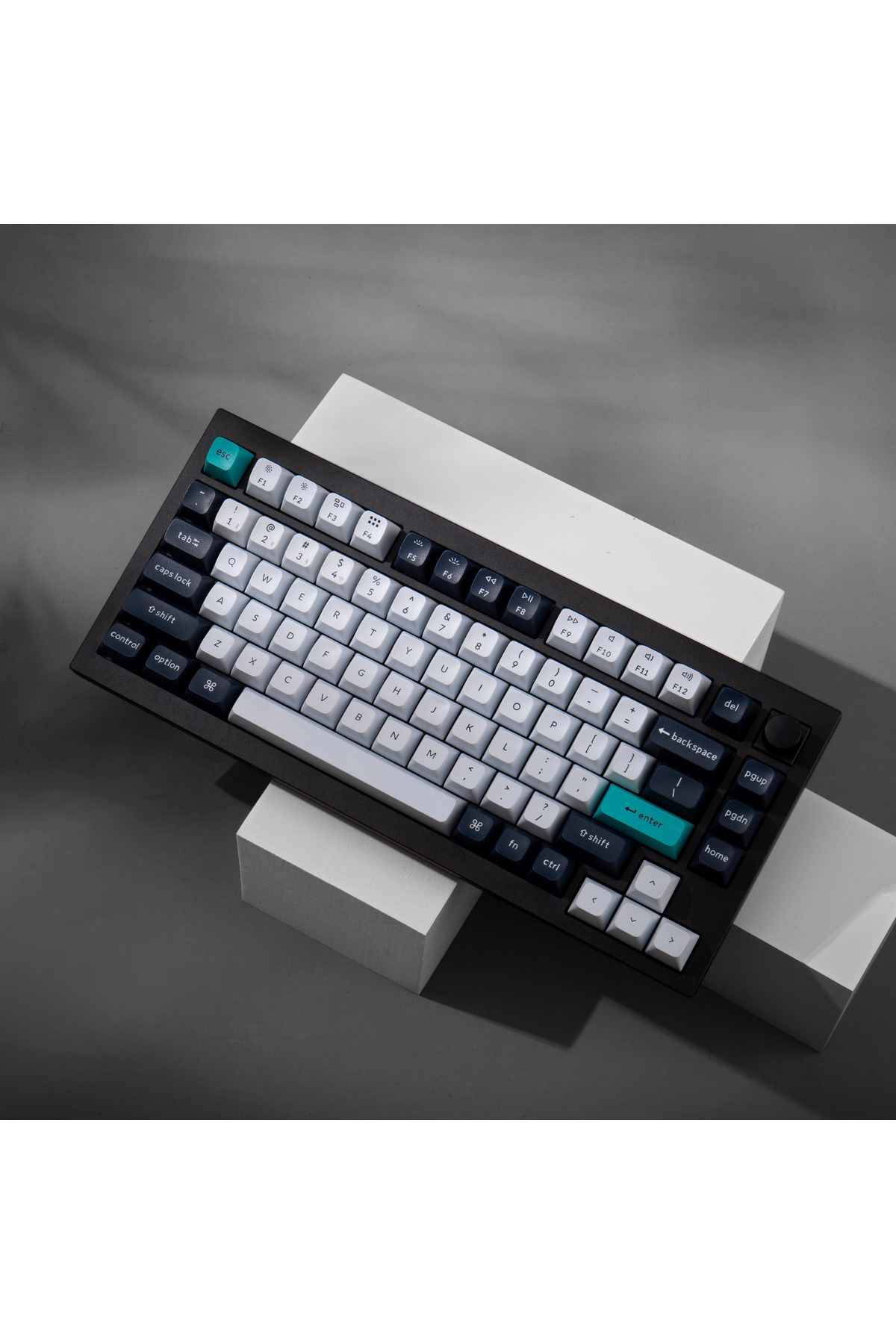 Un teclado negro con teclas blancas y azul oscuro, colocado sobre bloques blancos.
