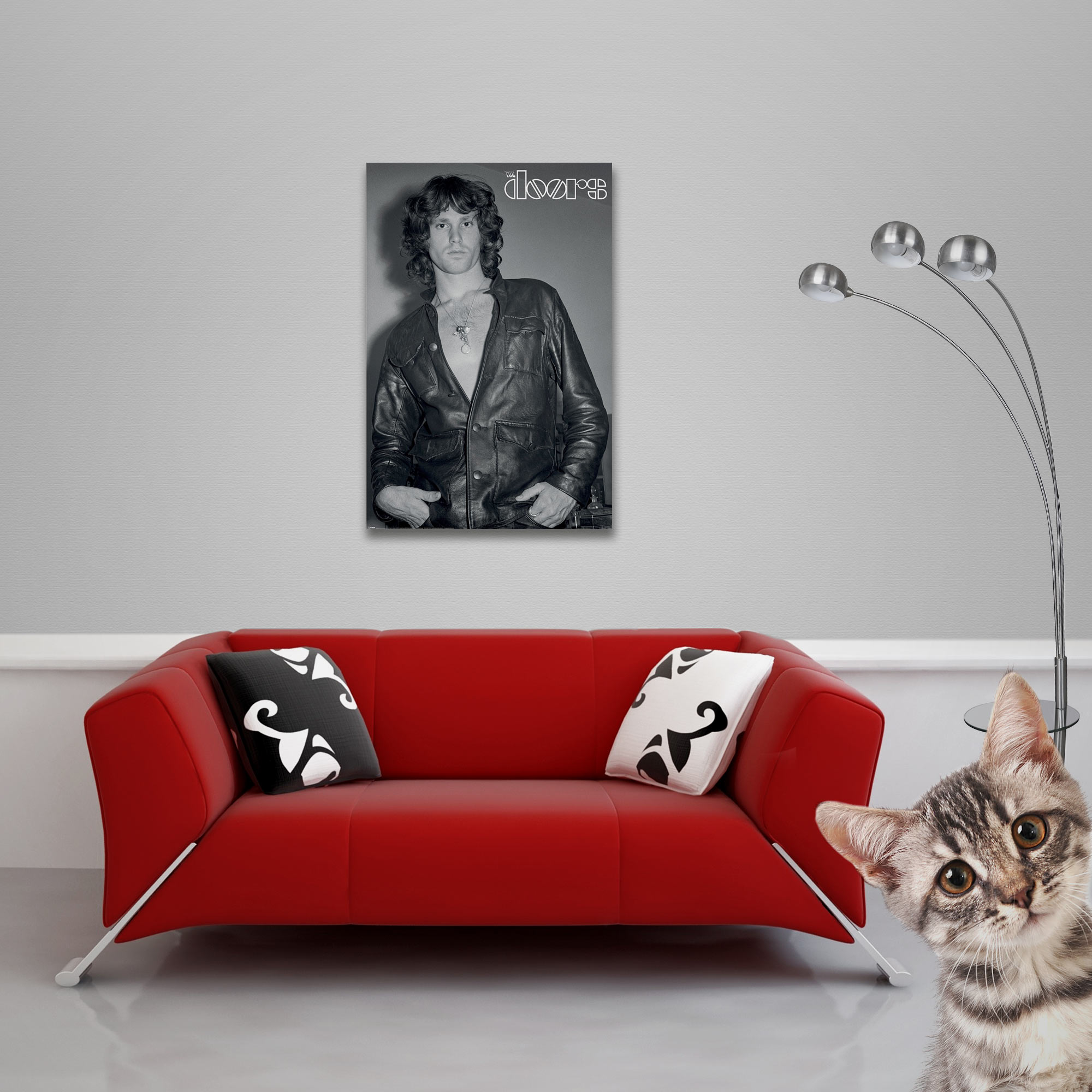 Ein Kater schaut auf eine rote Couch mit Kissen und einem Bild von Jim Morrison.