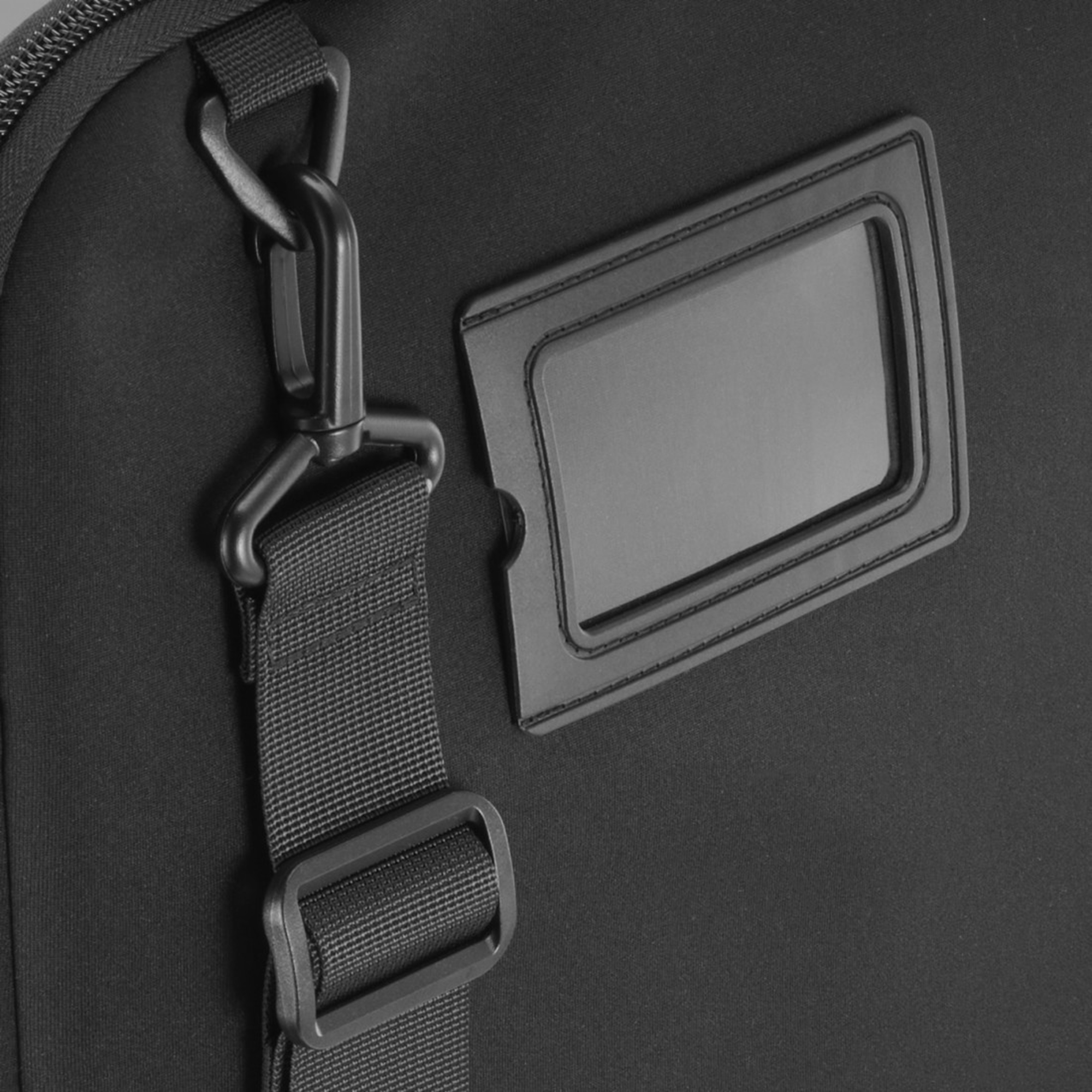 Czarna torba z regulowanym paskiem i uchwytem na identyfikator.