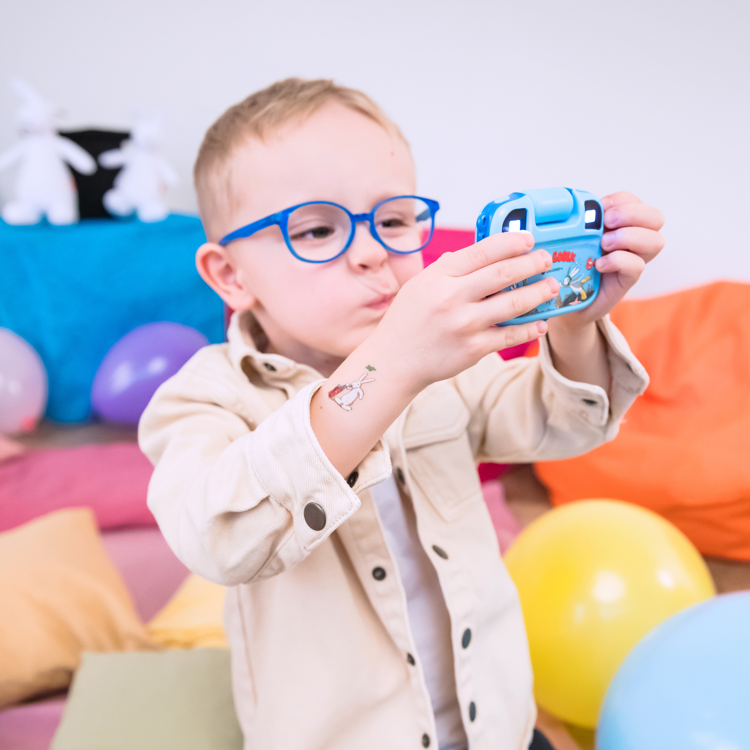 Junge mit blauen Brillen macht ein Foto mit einer blauen Kamera.