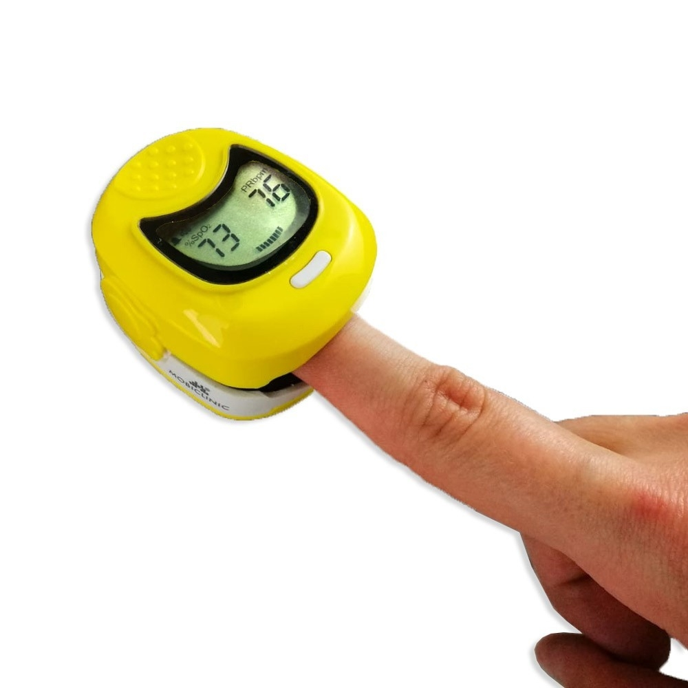 Un oxímetro de pulso amarillo mide el dedo de un hombre. La pantalla muestra 73% SpO2 y 76 BPM.