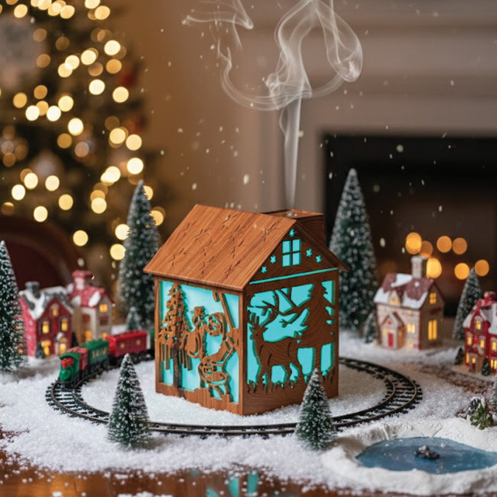 Tahta ev, Noel sahnesi, yükselen duman, kar, ağaçlar ve trenle çevrili.
