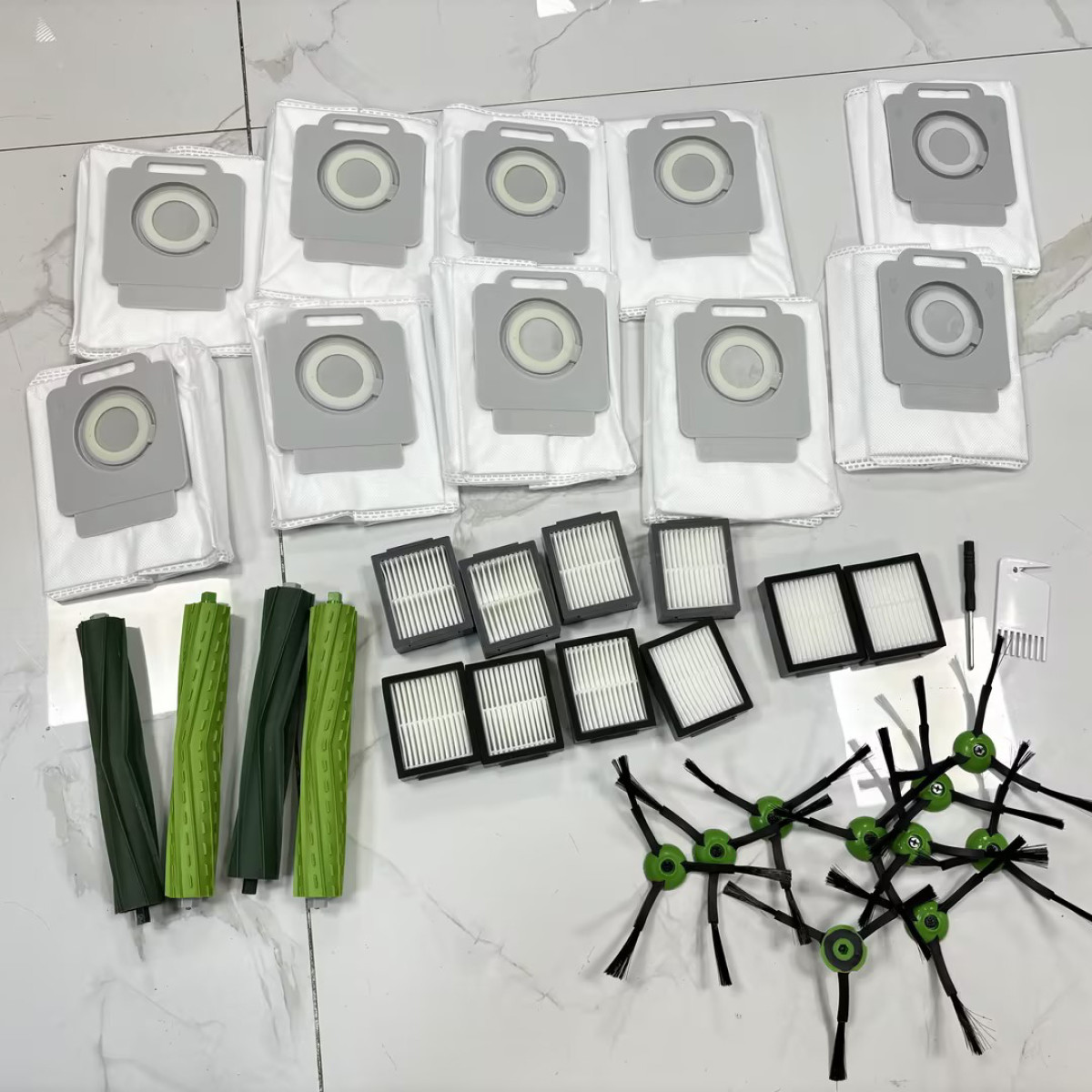 Akcesoria do odkurzacza: worki, filtry, szczotki i narzędzia na białej marmurowej podłodze.