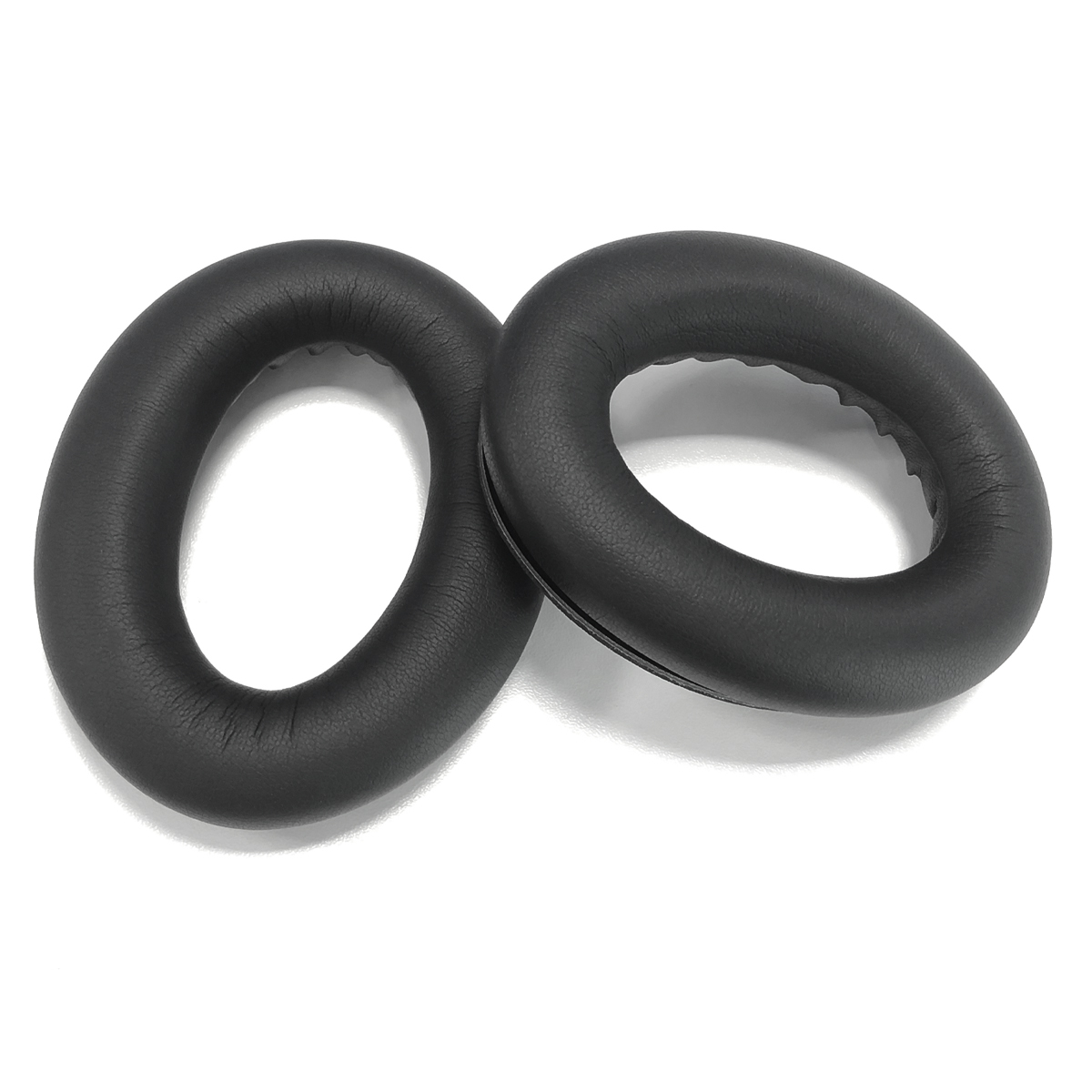 Dwa czarne nauszniki leżą obok siebie na białym tle.