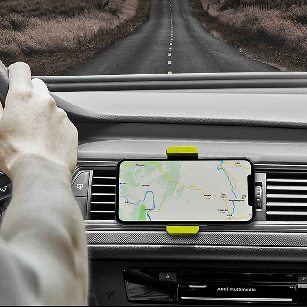 Mano en el volante, teléfono con mapa en el tablero, carretera al fondo.