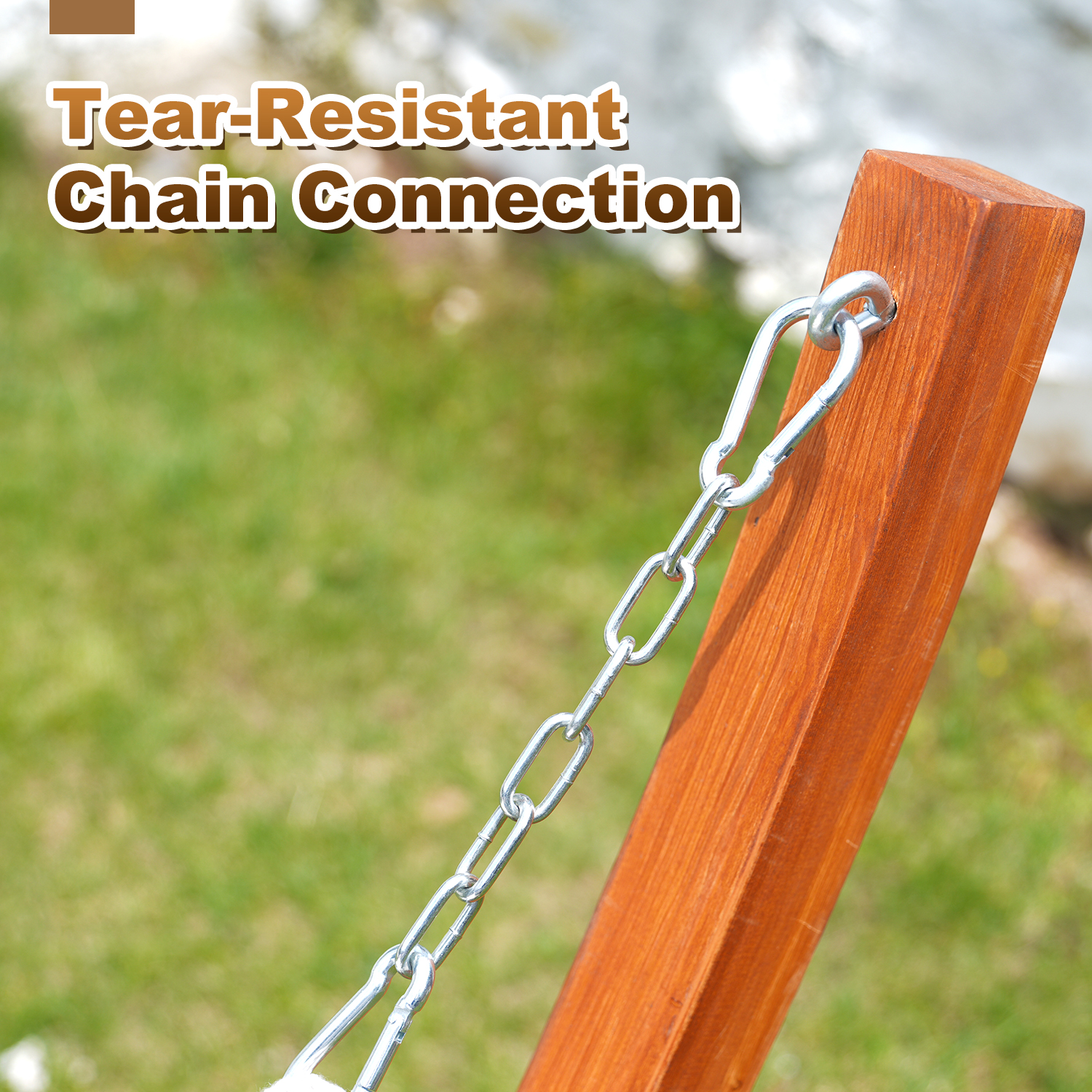 Łańcuch z karabińczykiem przymocowany do drewnianego słupka, trawa w tle.