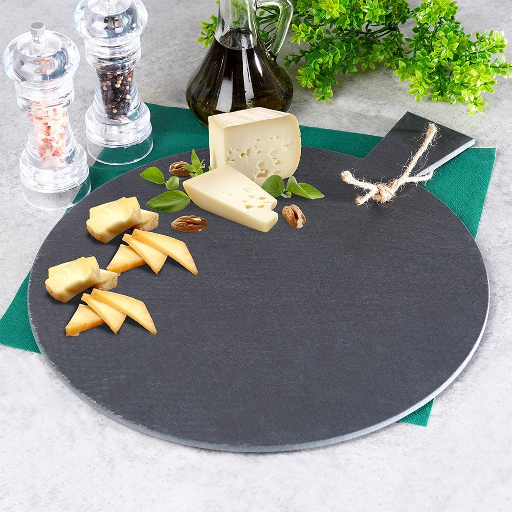 Tabla de quesos con surtido de quesos, nueces y hierbas sobre pizarra oscura.