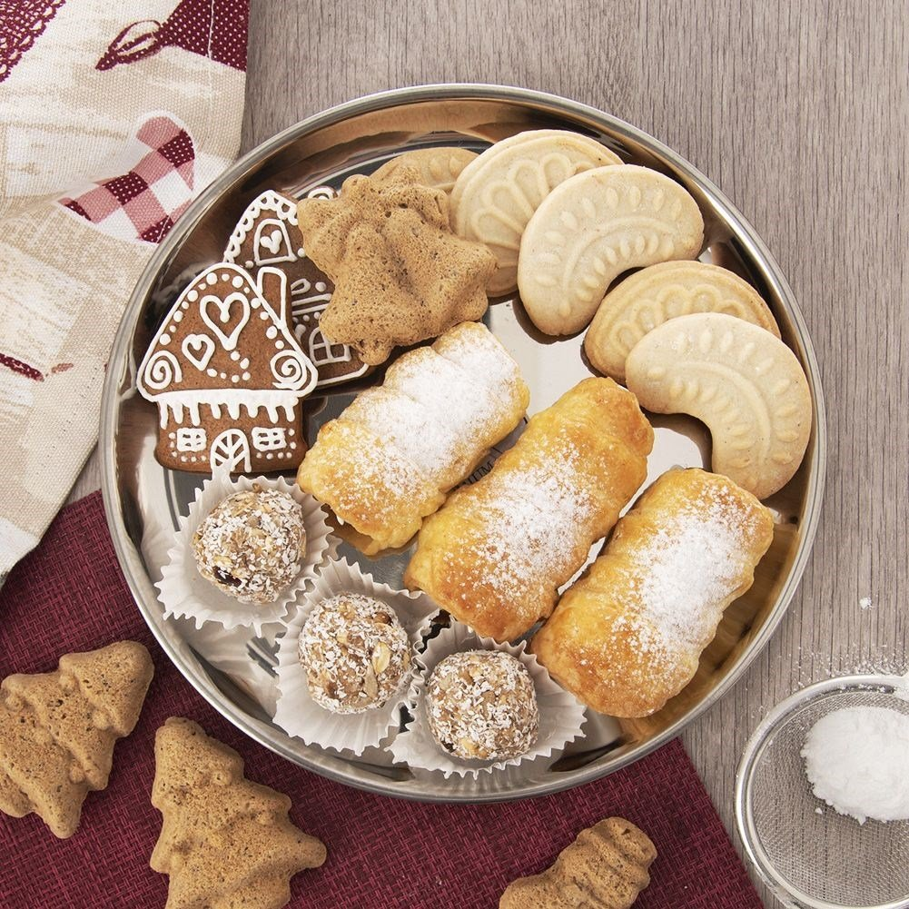 Una bandeja plateada con varias galletas navideñas, como casas de jengibre y rollos espolvoreados.