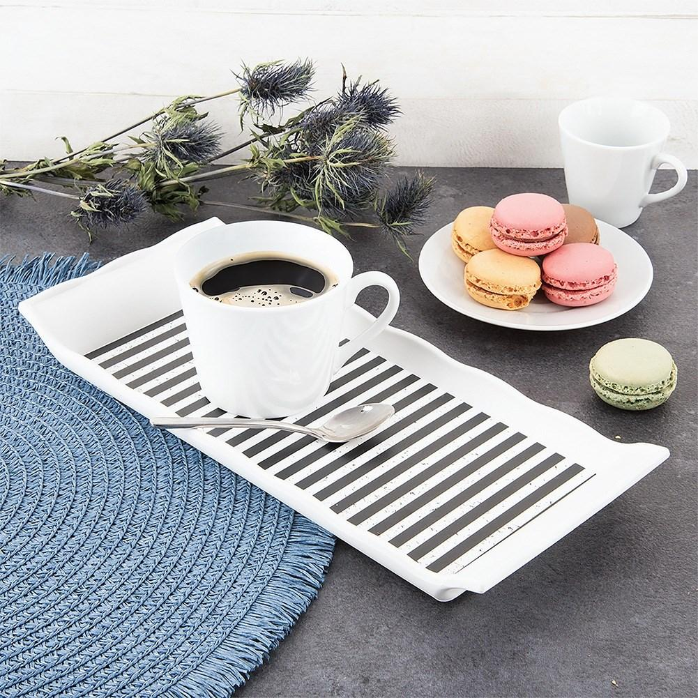 Café y macarons en una bandeja a rayas con un mantel individual azul.