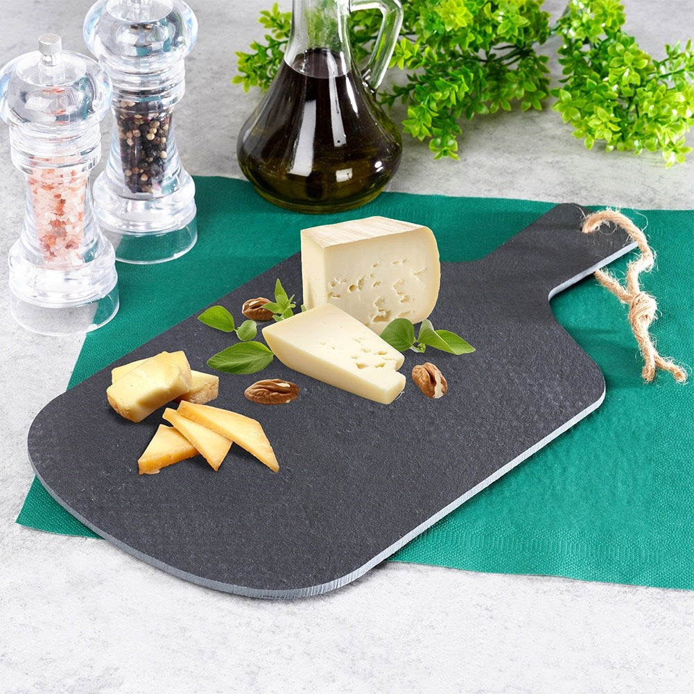 Tabla de quesos con varios quesos, nueces y hierbas en una tabla de pizarra.