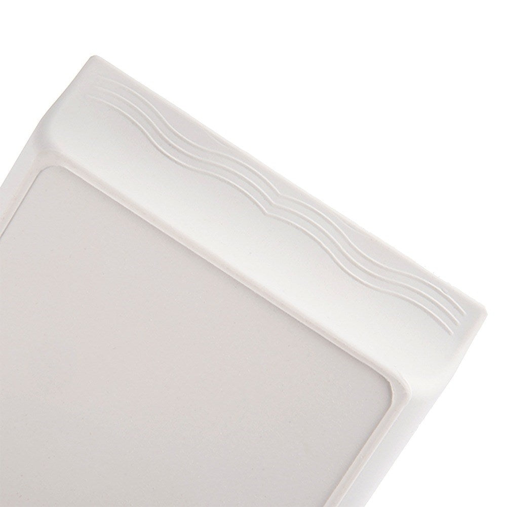 Primer plano de una caja rectangular blanca con detalles repujados ondulados en el borde.