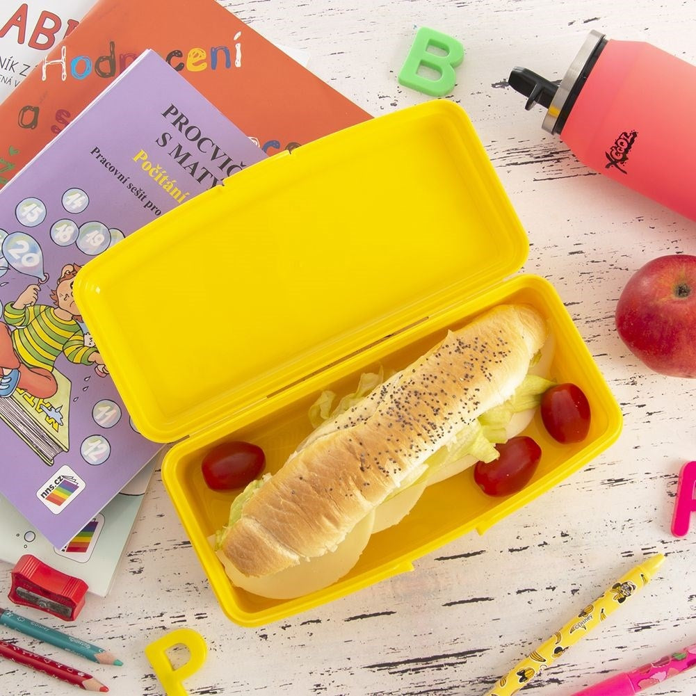 Una lonchera amarilla con un sándwich, manzana, libros y bolígrafos.