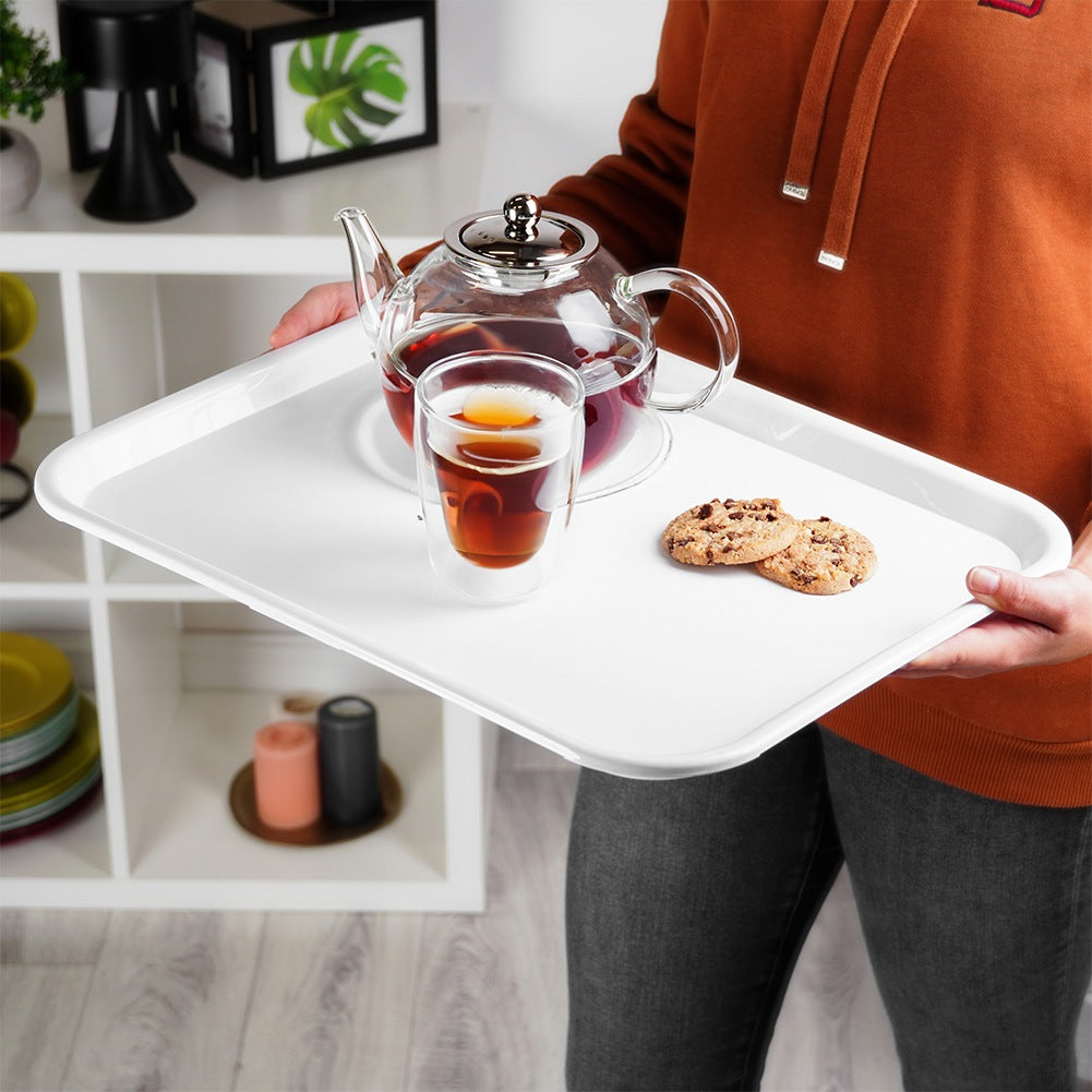 Una persona sostiene una bandeja con tetera, vaso de té y dos galletas.