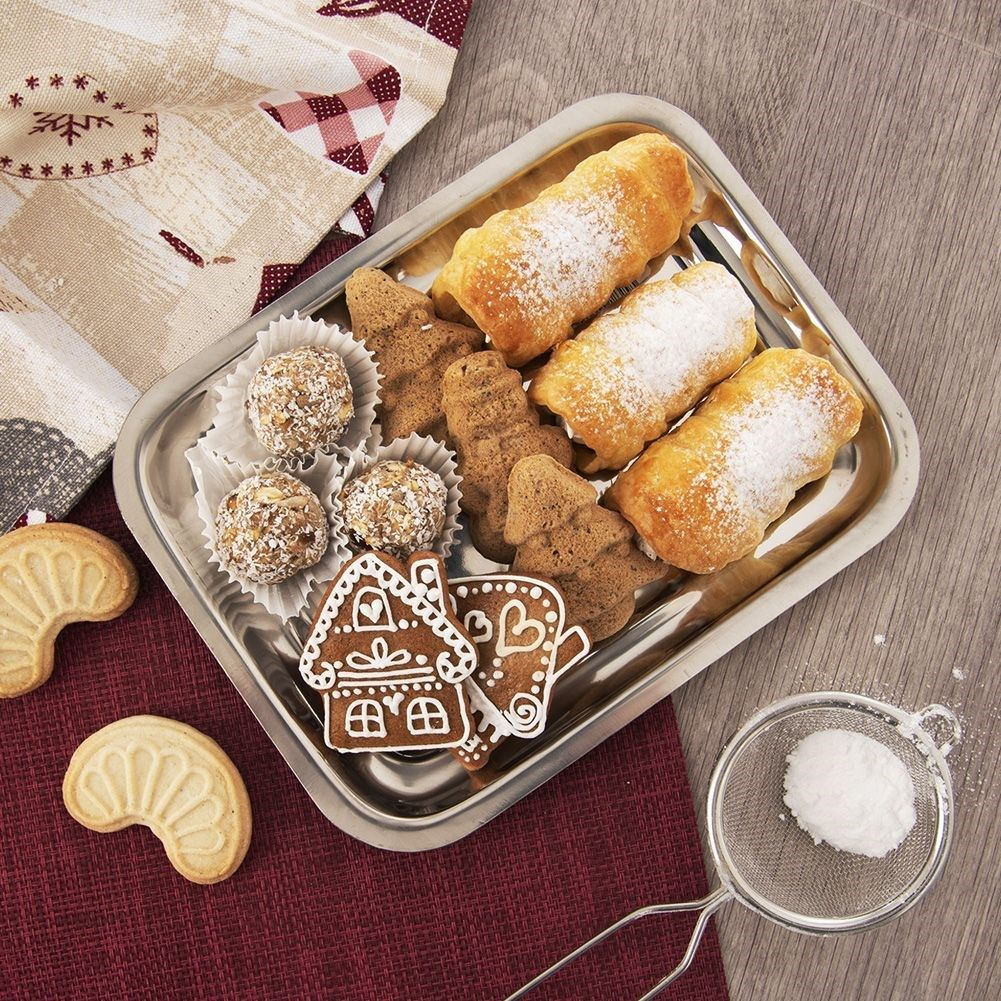 Bandeja plateada con dulces navideños: galletas, casas de jengibre, rollos de crema, espolvoreados.