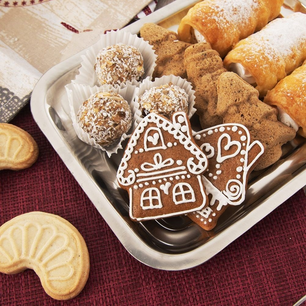 Una bandeja de plata con varias galletas y pasteles, incluyendo casas de jengibre y rollos de crema.