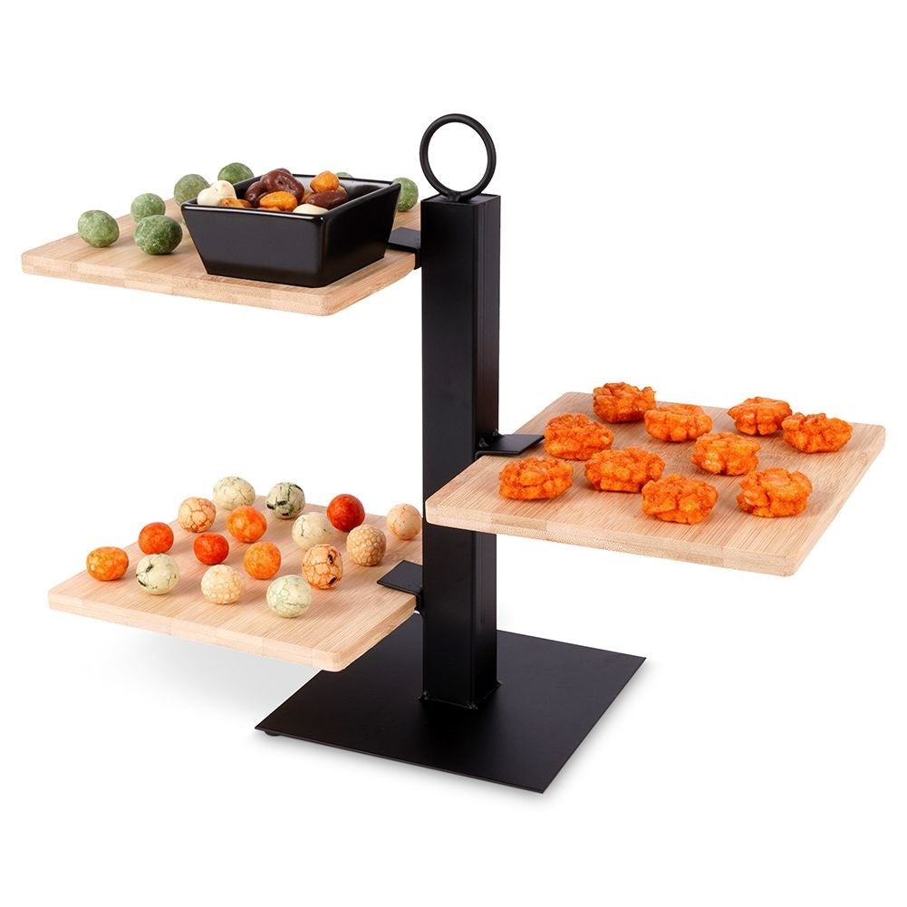 Un soporte negro de niveles con tres bandejas de madera con bocadillos.