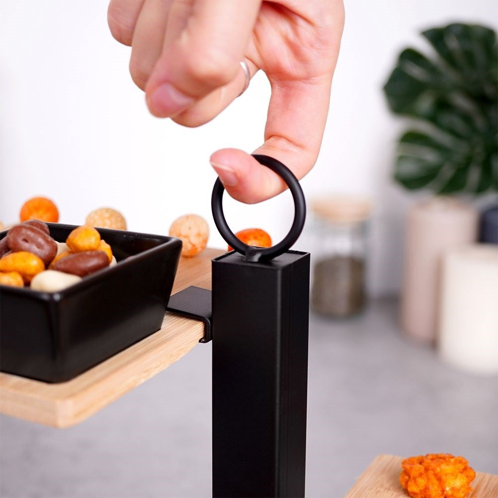 Un dedo sostiene un anillo negro en un soporte negro sobre un cuenco de aperitivos.
