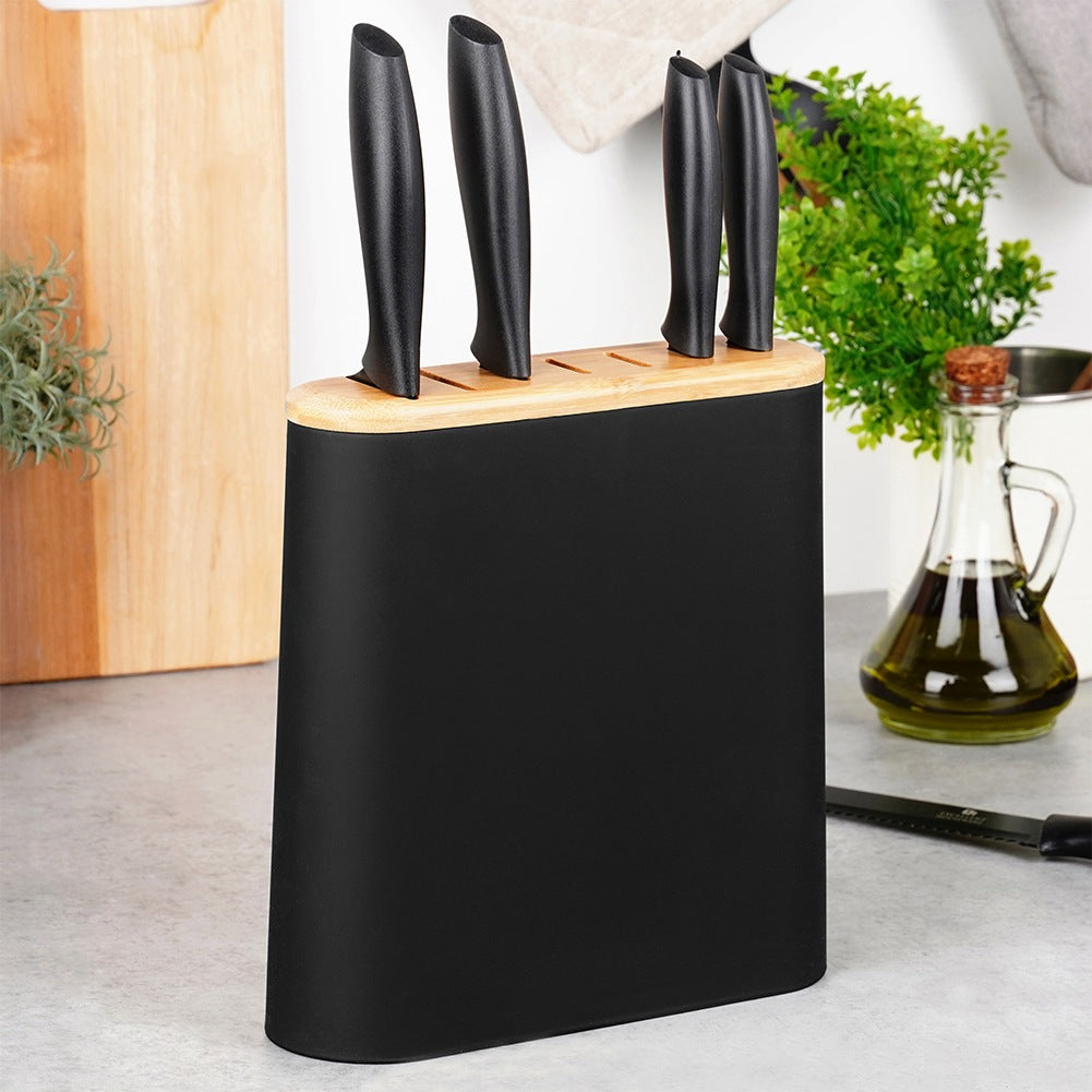Un bloque de cuchillos negro con tapa de madera y cuchillos, junto a una aceitera.