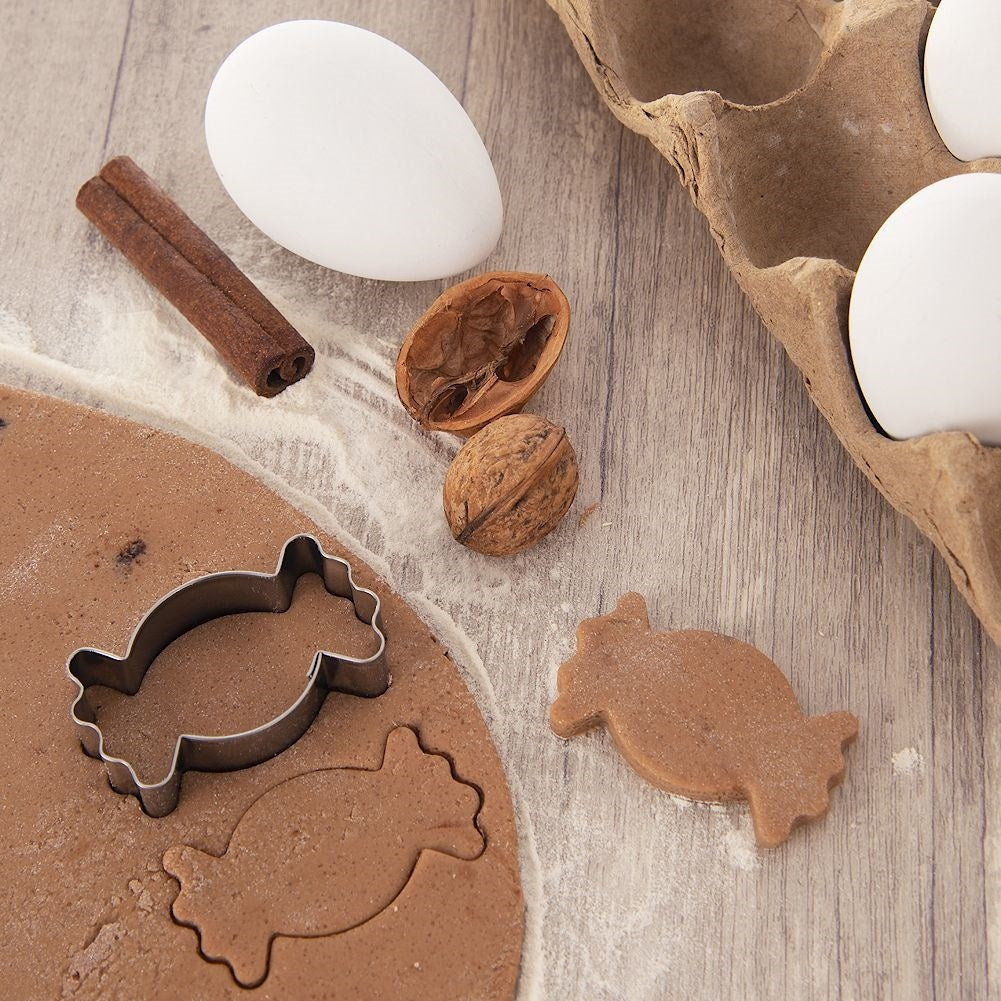 Un huevo, canela, nueces y cortadores de galletas sobre masa.