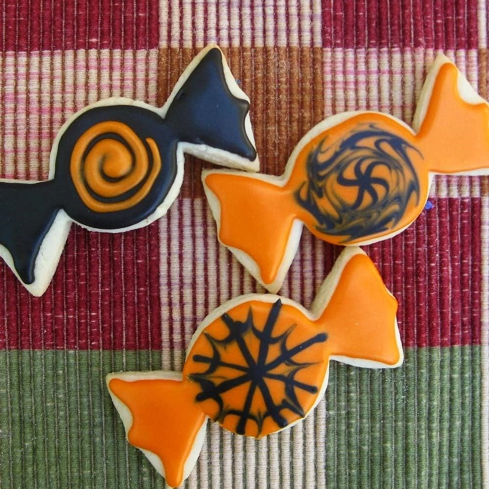 Tres galletas con forma de caramelo de Halloween sobre fondo de cuadros.