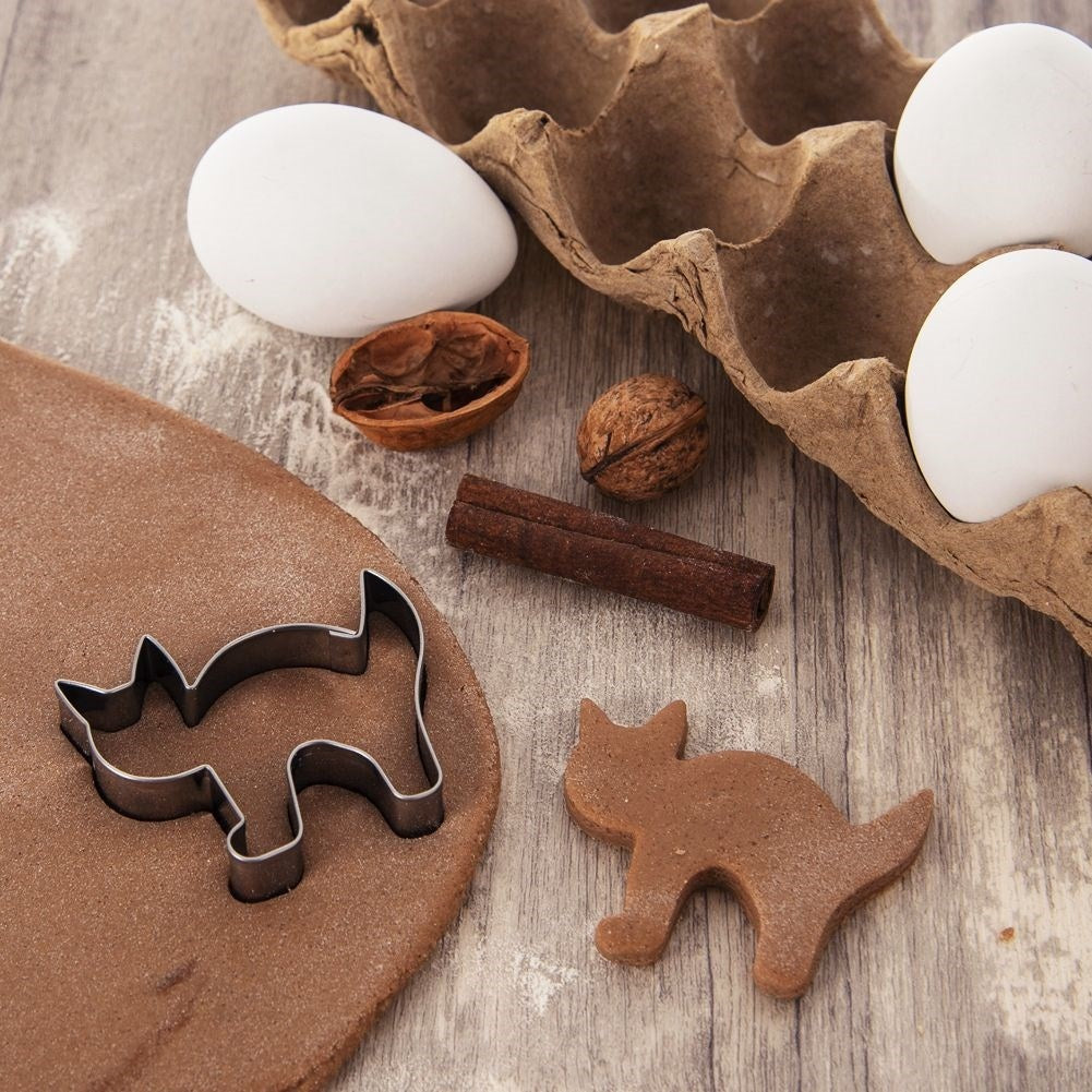 Cortador de galletas con forma de gato en masa, con huevos, nueces y canela.