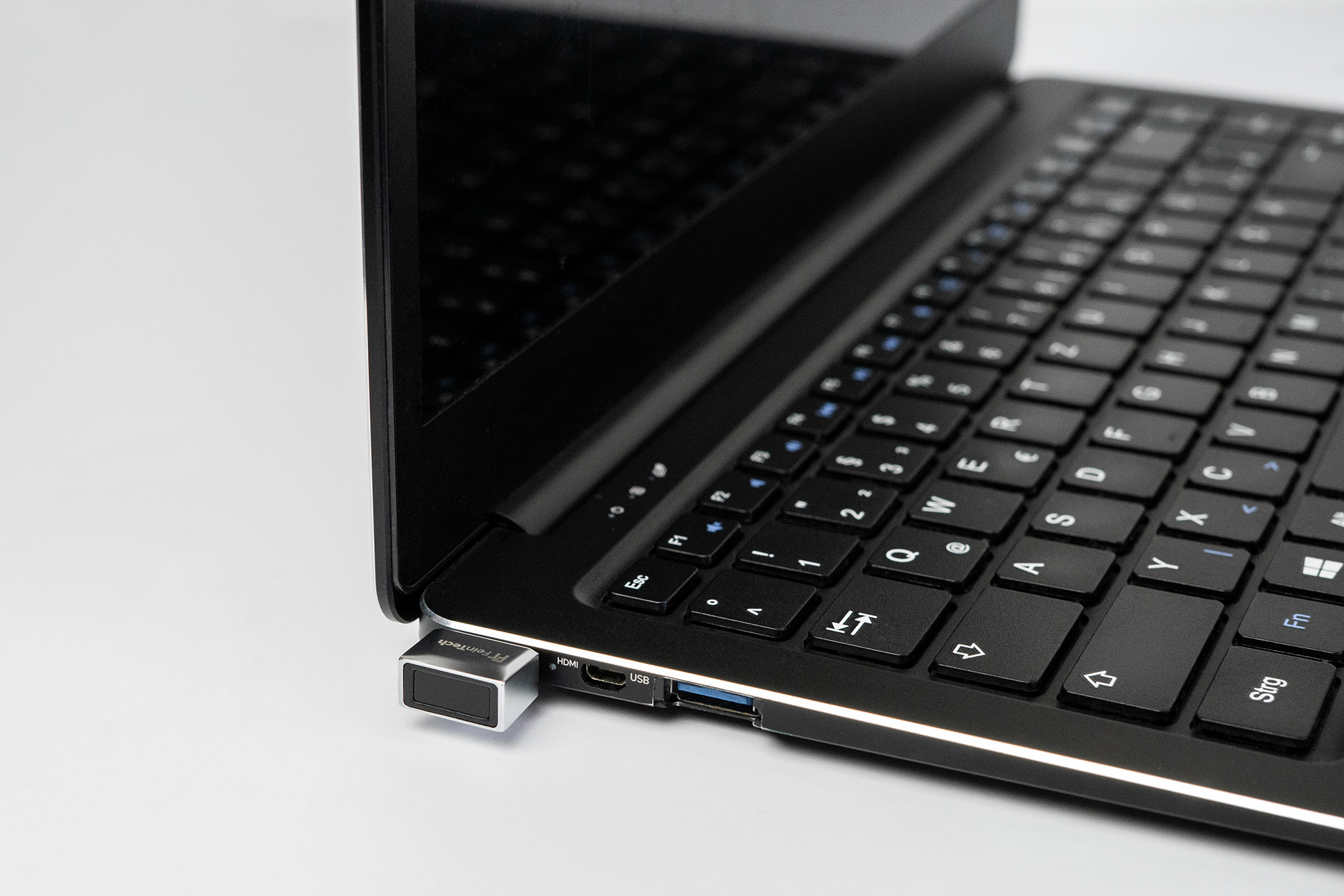 Un lettore di impronte digitali USB è collegato a un laptop accanto alla tastiera.