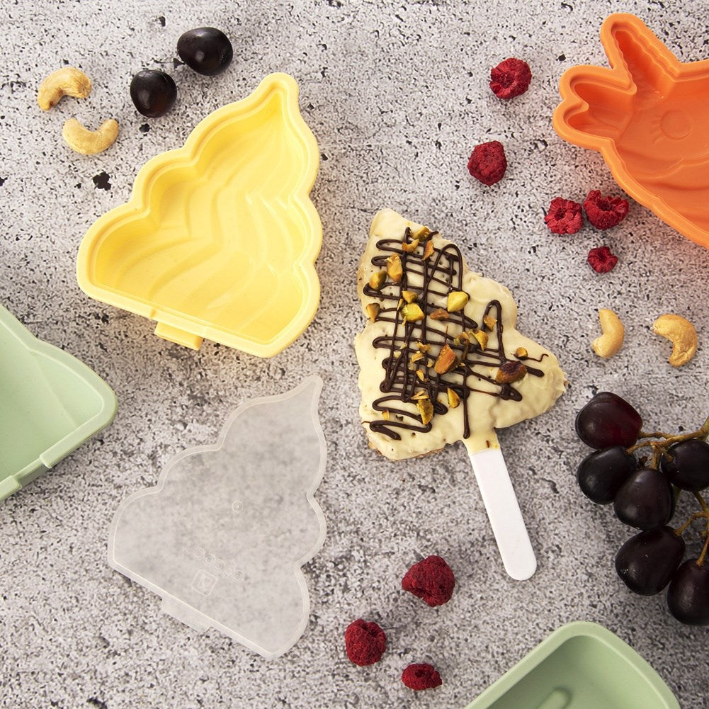 Moldes de hielo en forma de árbol, helado decorado, bayas, nueces y uvas sobre fondo gris.